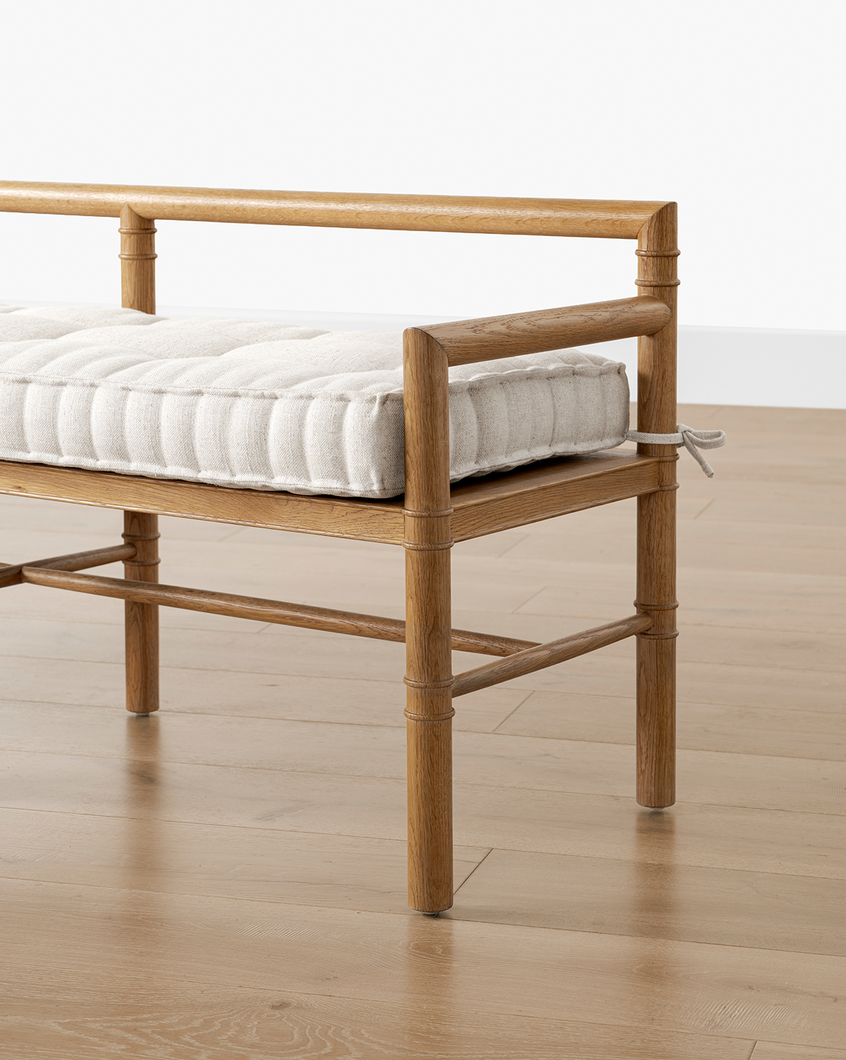 The Hindley Bench features a neatly tufted upholstered cushion, a light brown solid wood frame, and is shown on a light wood floor against a white wall, by Vendixs