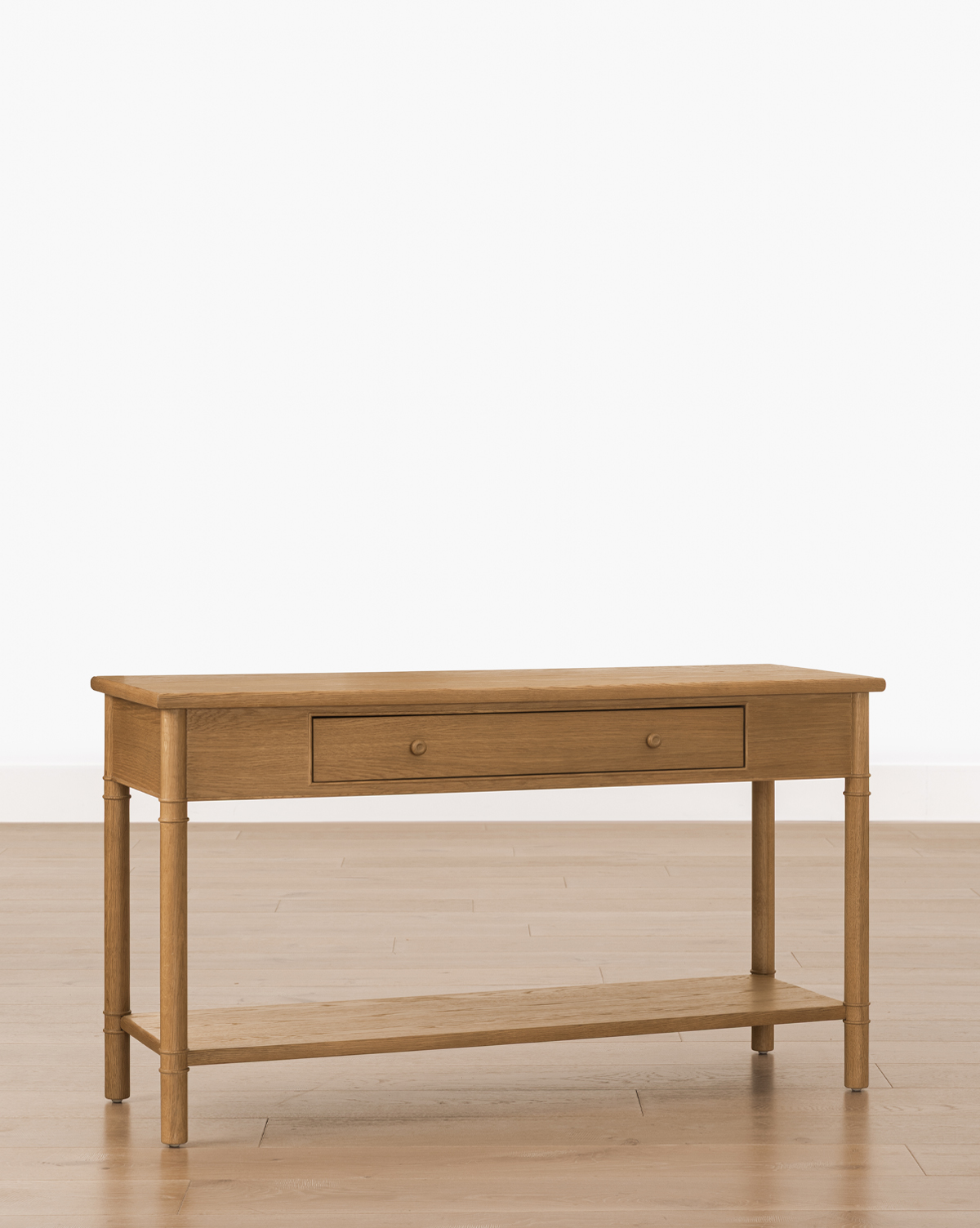 The Hindley Console features an oak finish, single central drawer, four legs, and a lower shelf for stylish storage. It is displayed on a light wooden floor against a plain white background, by Vendixs
