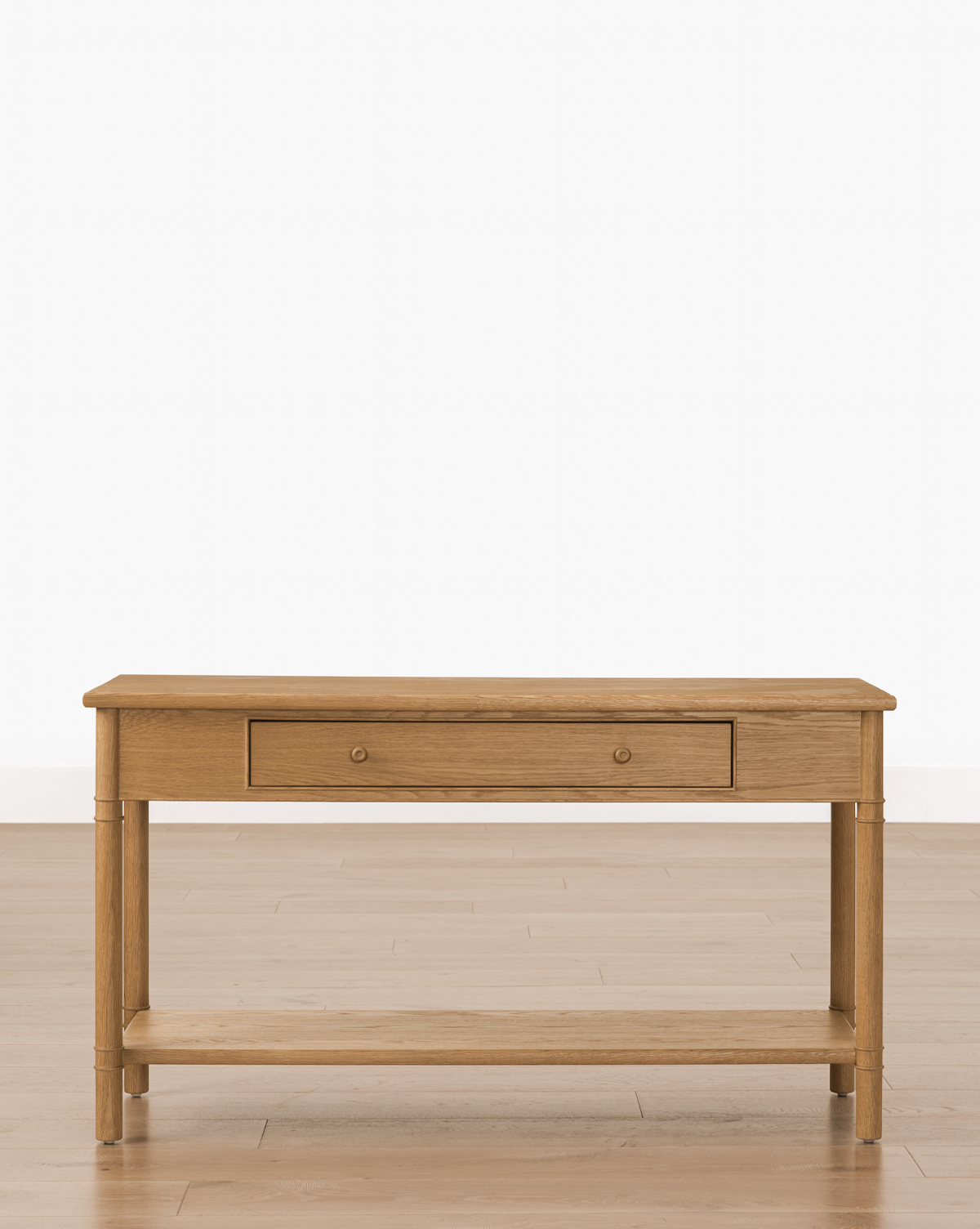 The Hindley Console, featuring an oak finish, a central drawer, and a lower shelf, is perfect as an entryway table. Shown on a wooden floor against a plain white background, by Vendixs