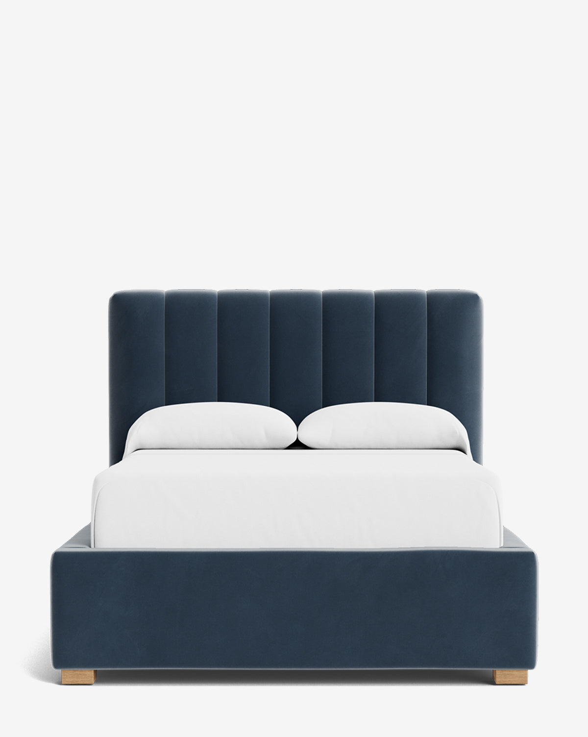 The Hoffman Bed Low Headboard is a modern upholstered bed with a low dark blue headboard, wooden legs, and crisp white bedding with two pillows, displayed against a plain white background by McGee & Co.