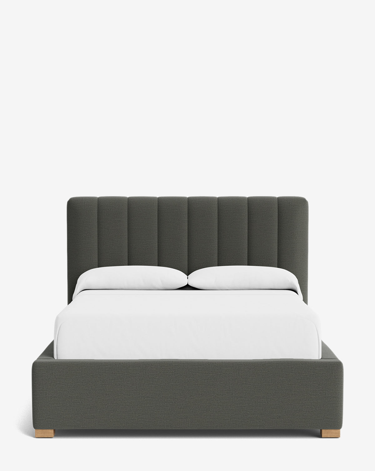 The Hoffman Bed Low Headboard is a modern dark gray upholstered frame with a customizable low headboard featuring vertical channel tufting, light wood legs, and white bedding and pillows set against a plain white background by McGee & Co.