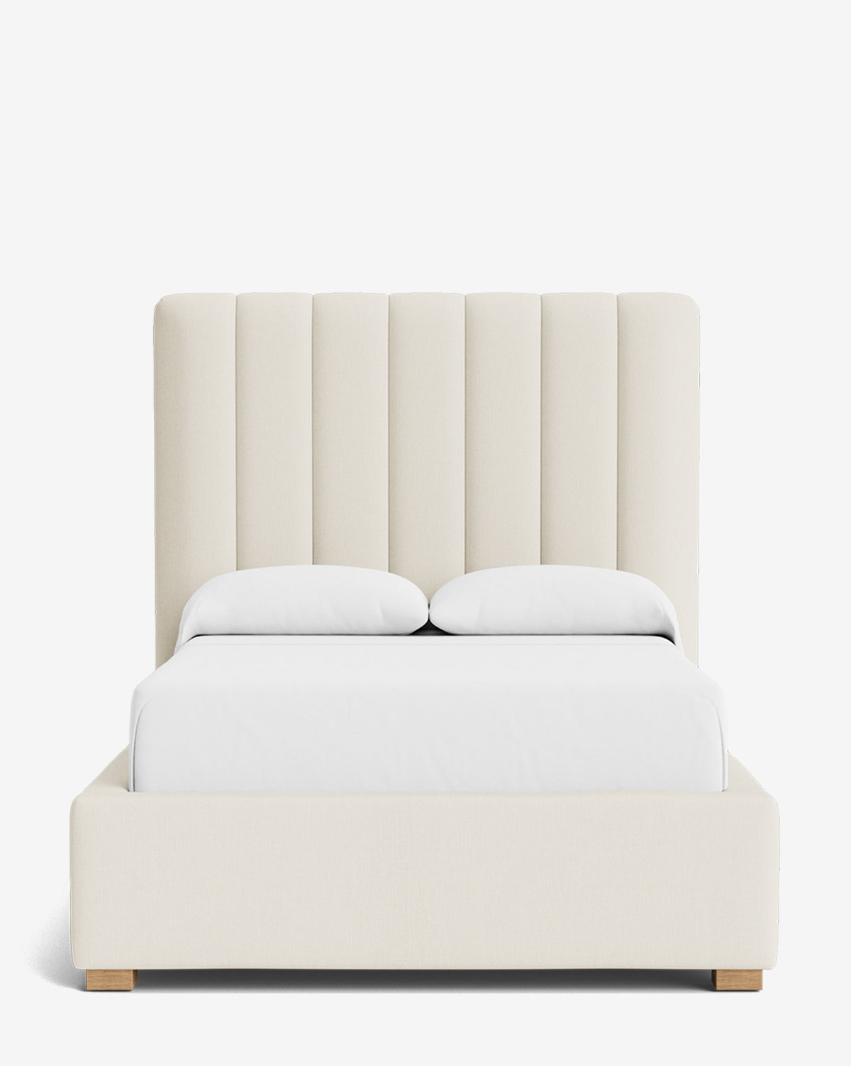 The Hoffman Bed Tall Headboard features vertically paneled, cream upholstery, white bedding, and a low upholstered frame on wooden legs. Available in customizable fabrics to match your style by McGee & Co.