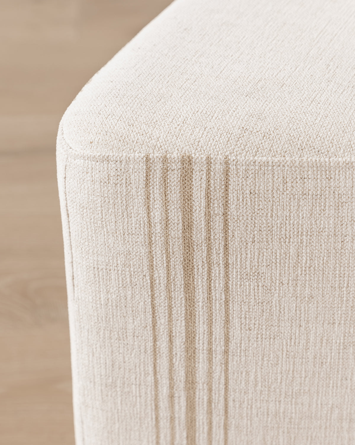 Close-up of a beige Jacques Ottoman by Dongguan City Baby Furniture Co., Ltd in Crypton striped fabric with vertical stitched lines, set on a wooden floor—ideal for stylish durability in kids’ rooms, Vendixs
