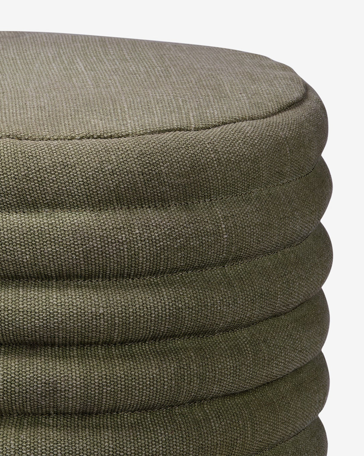 Close-up of the Made Goods Jefferson Stool, a round quilted design in olive green with textured fabric, horizontal stitched seams, and a soft cushioned top, shown against a white background. Vendixs