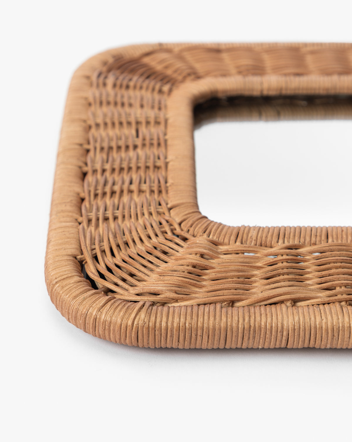 Close-up of a corner of the Jera Shelf Mirrors square, woven rattan frame in natural light brown, highlighting its detailed weaving patterns and texture against a white background by Vendixs