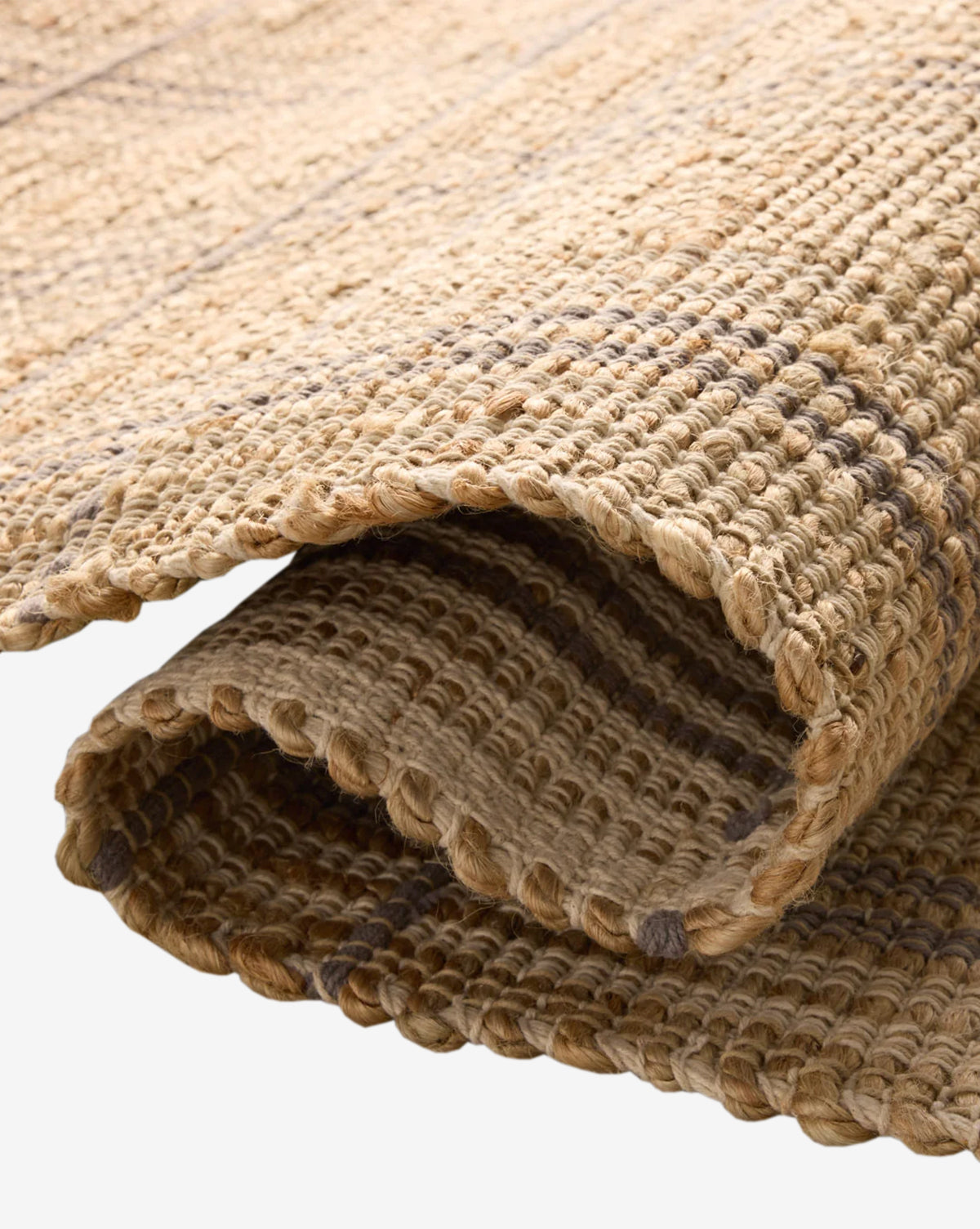 A close-up of the Judy Jute Rug Collection No. 2 showcases its handwoven, thick braided natural fibers in earthy brown tones and textured surface, all in a neutral palette, by Vendixs