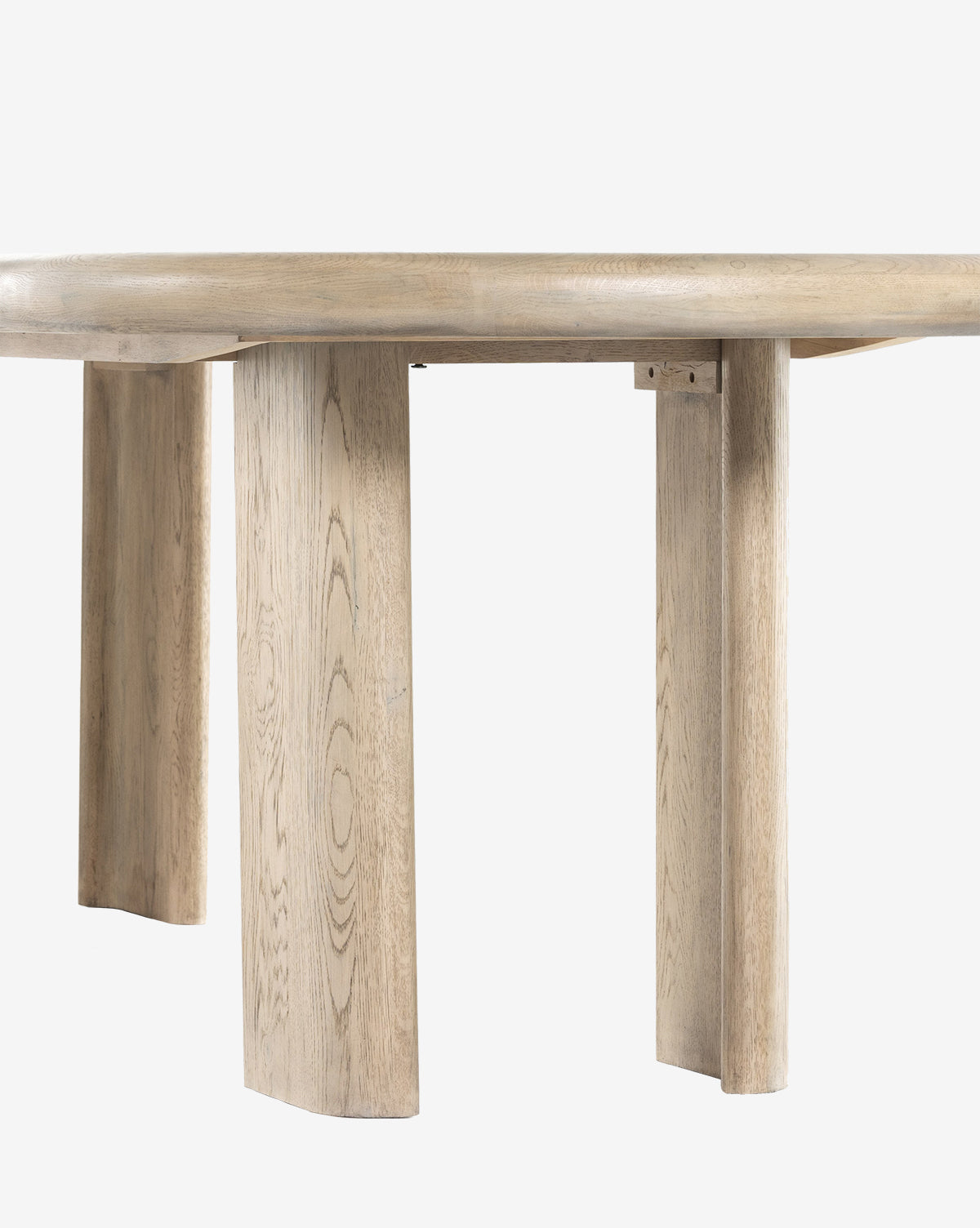 A close-up of the Juliana Extension Dining Table reveals its round solid oak top and three wide, flat legs with natural wood grain, highlighting modern design against a plain white background by McGee & Co.