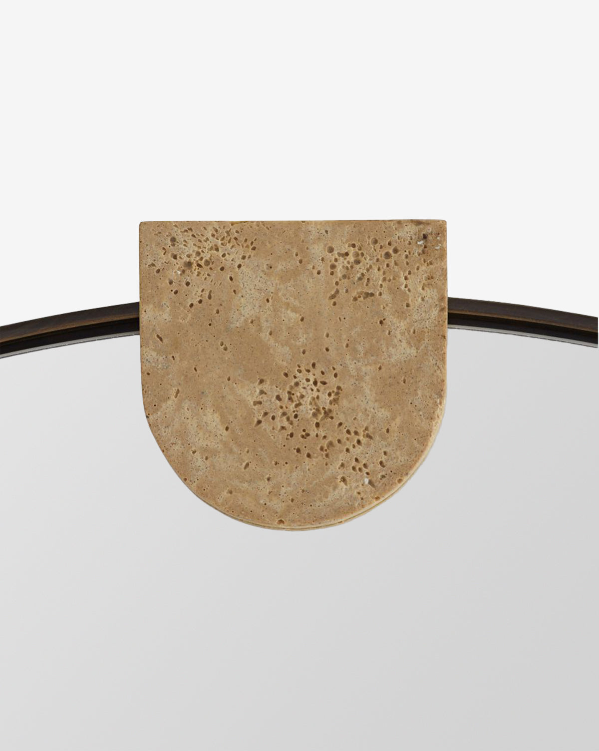 A close-up of the Kairos Mirror, showcasing its round shape with a semi-circular faux travertine accent on top and a natural, textured finish, by Vendixs