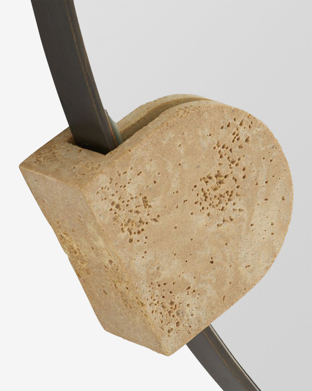 The Kairos Mirror features a close-up of its textured faux travertine block, set against a curved, bronze-plated steel frame on a plain light background, by Vendixs