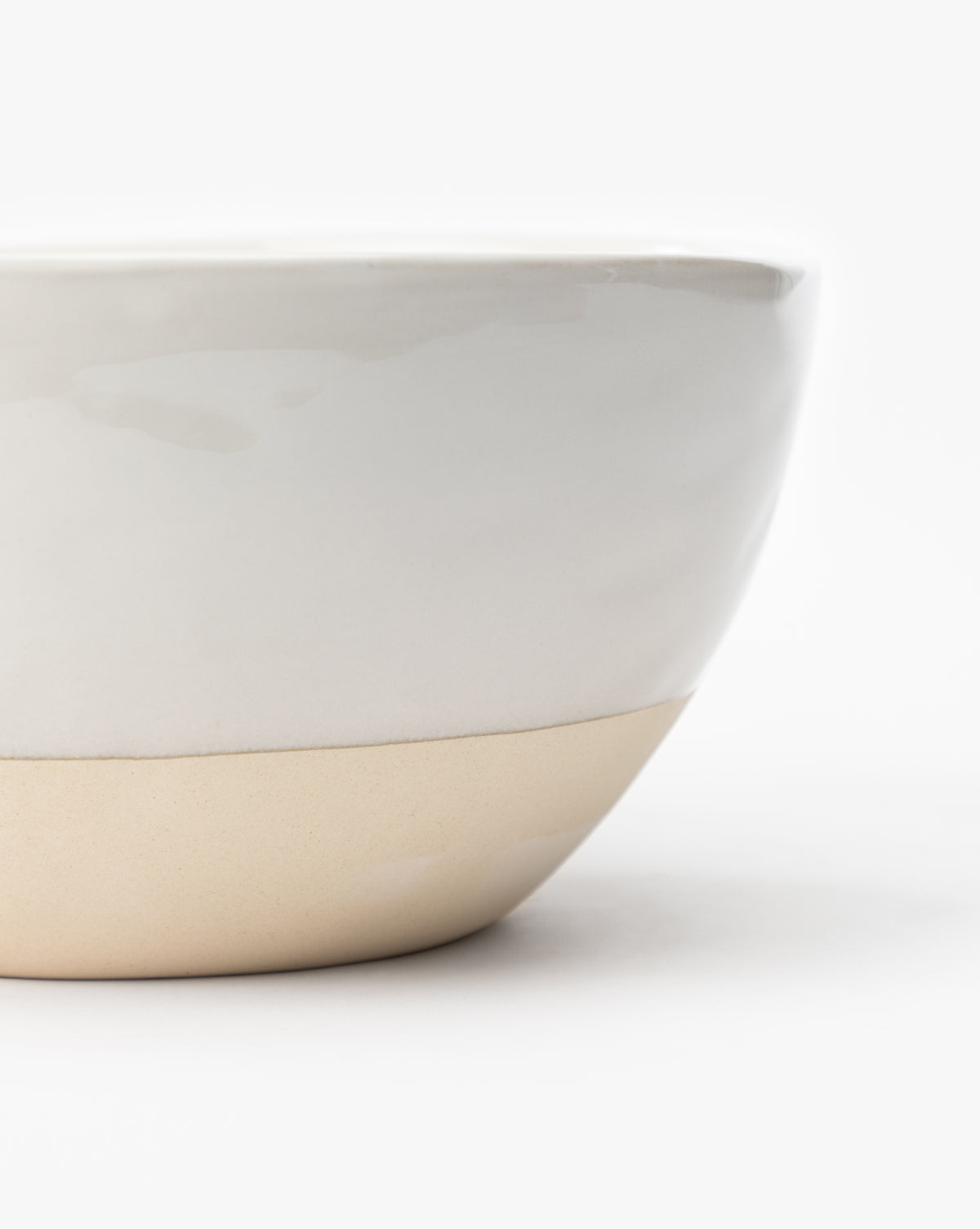 A close-up of the Karina Stoneware Batter Bowls (Set of 4), featuring a white glossy upper half and unglazed beige lower half, set against a plain background, evokes vintage baking charm, by Vendixs