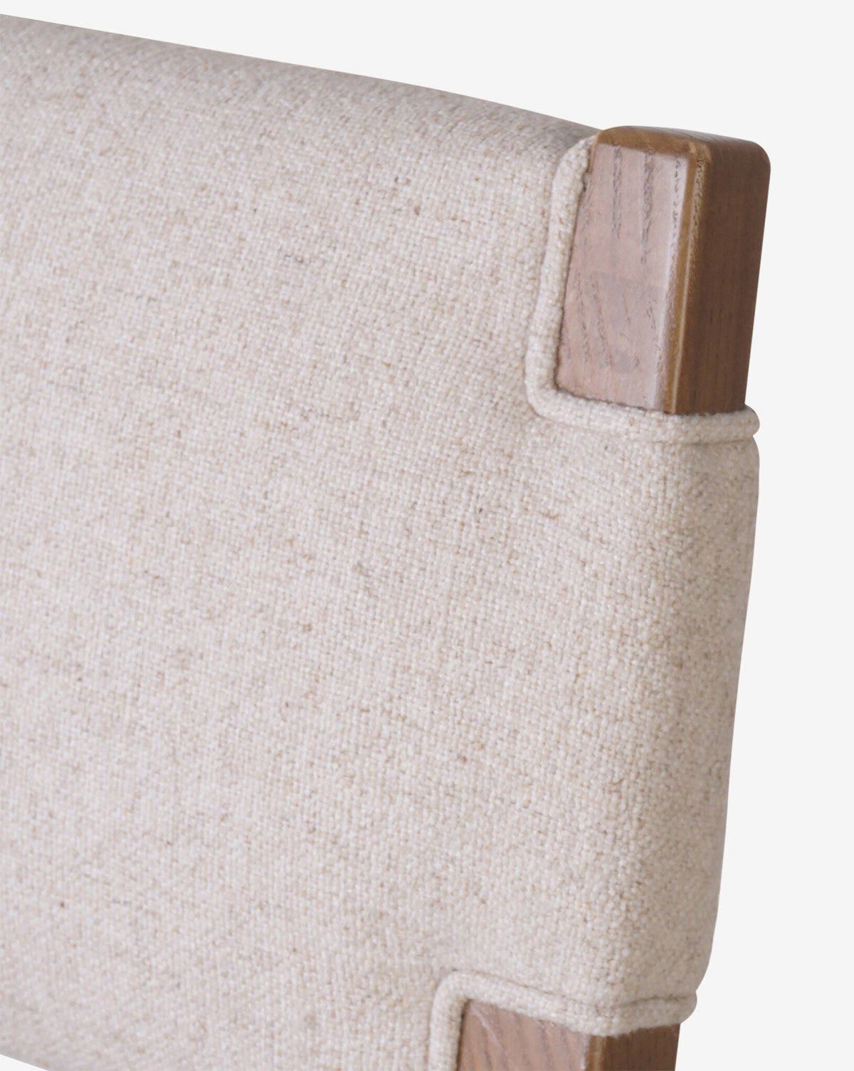 Close-up of the Kennebec Stool by Four Hands, featuring a beige performance fabric backrest and a visible ash wood frame at the corners. Vendixs