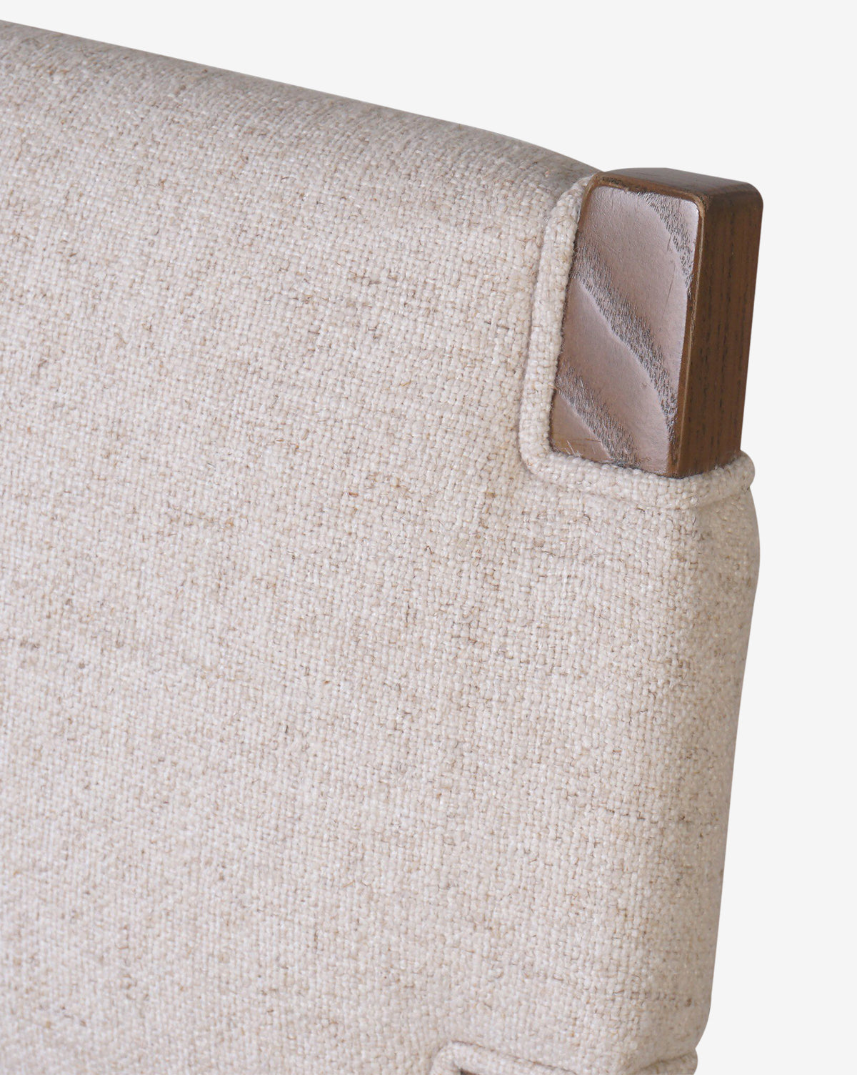 Close-up of the Kennebec Stool by Four Hands shows a beige performance fabric backrest with a wooden corner accent, highlighting the texture and rich ash grain detail. Vendixs