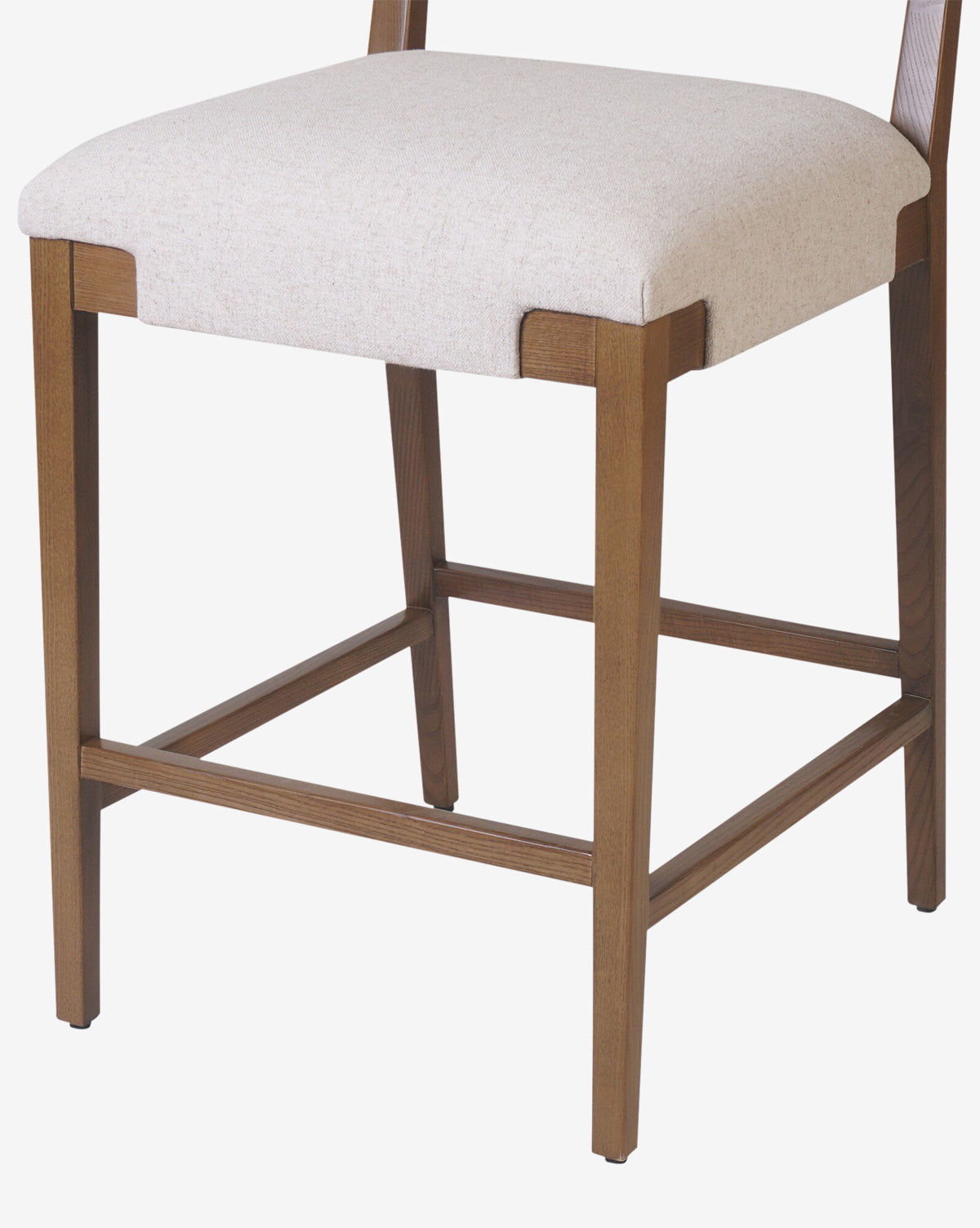 The Kennebec Stool by Four Hands features a close-up of its ash wood frame, straight legs with horizontal supports, and a light beige performance fabric upholstered seat. Vendixs