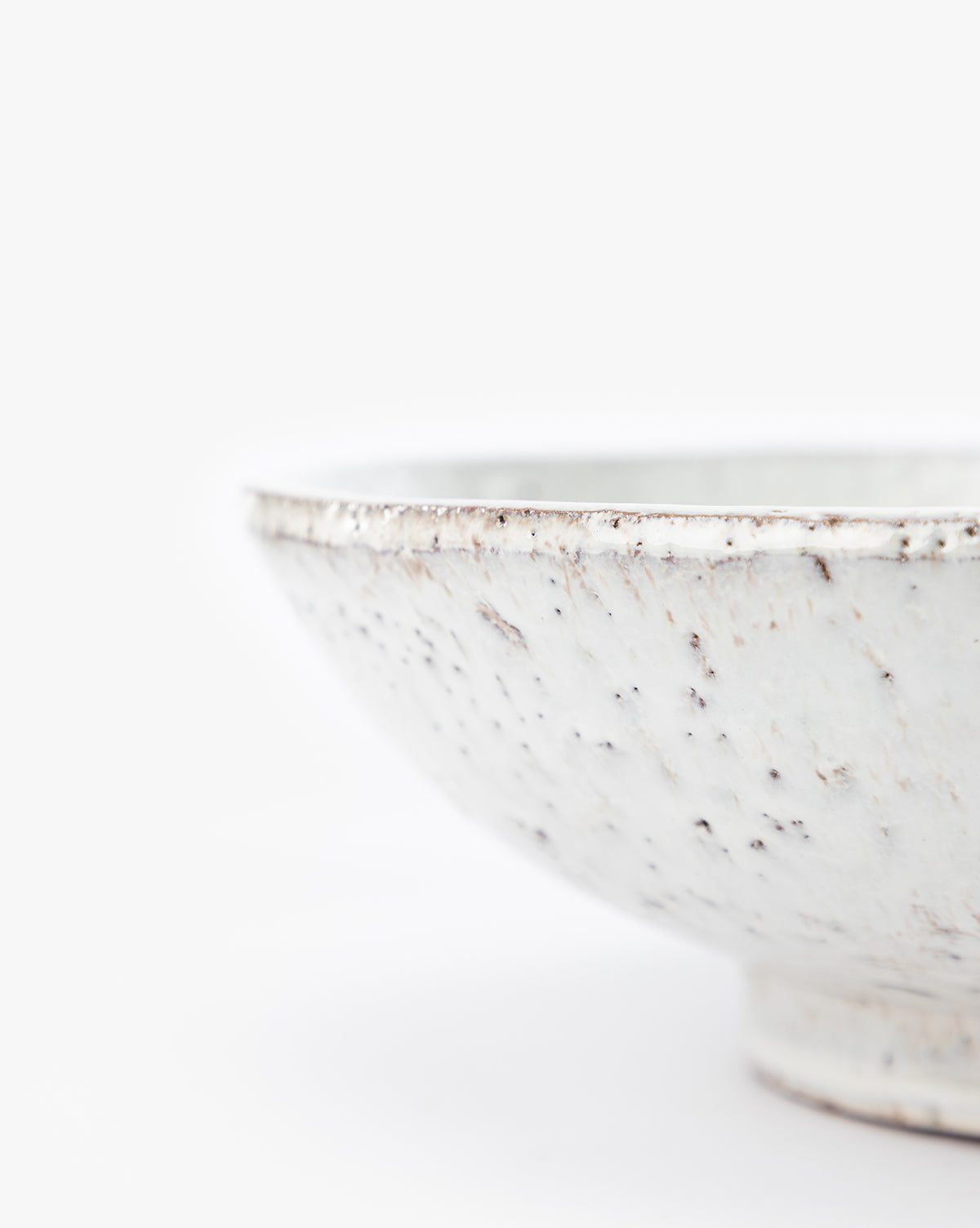 A close-up of the Kimpton Ceramic Bowl with a white speckled finish, photographed against a plain white background. The partially visible rim and textured surface highlight its decorative design, by Vendixs