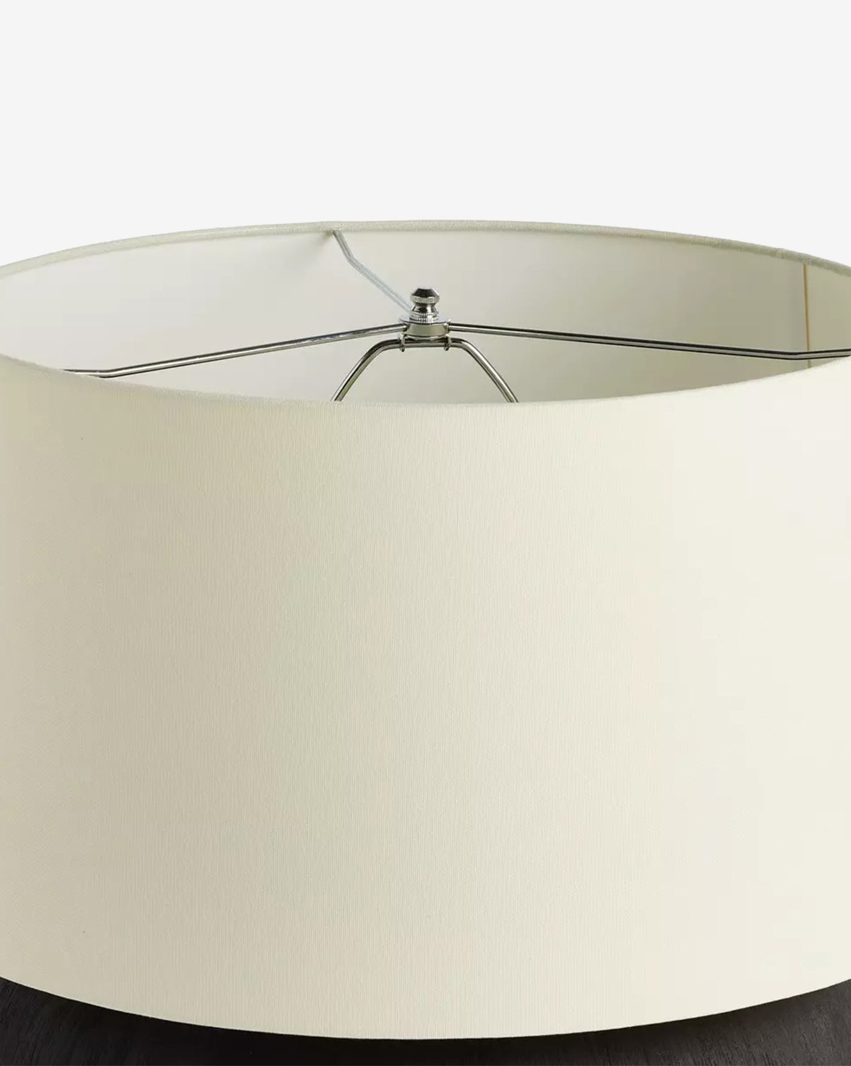 A close-up of the Kragen Table Lamp with a round ivory linen shade and visible metal framing, placed on a dark surface against a white background, by Vendixs