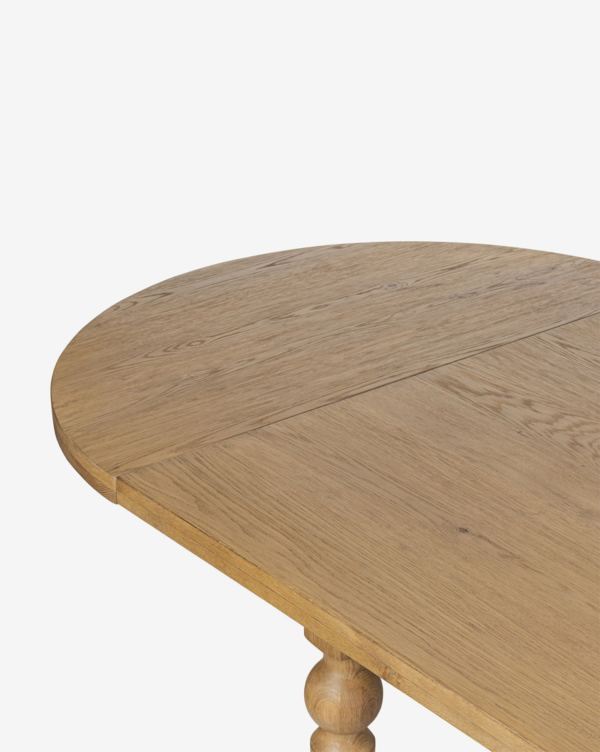 A close-up of the Kyler Oak Extension Dining Table highlights its light brown finish, rounded edge, smooth wood grain, and the visible seam on its extendable oval surface, by Vendixs