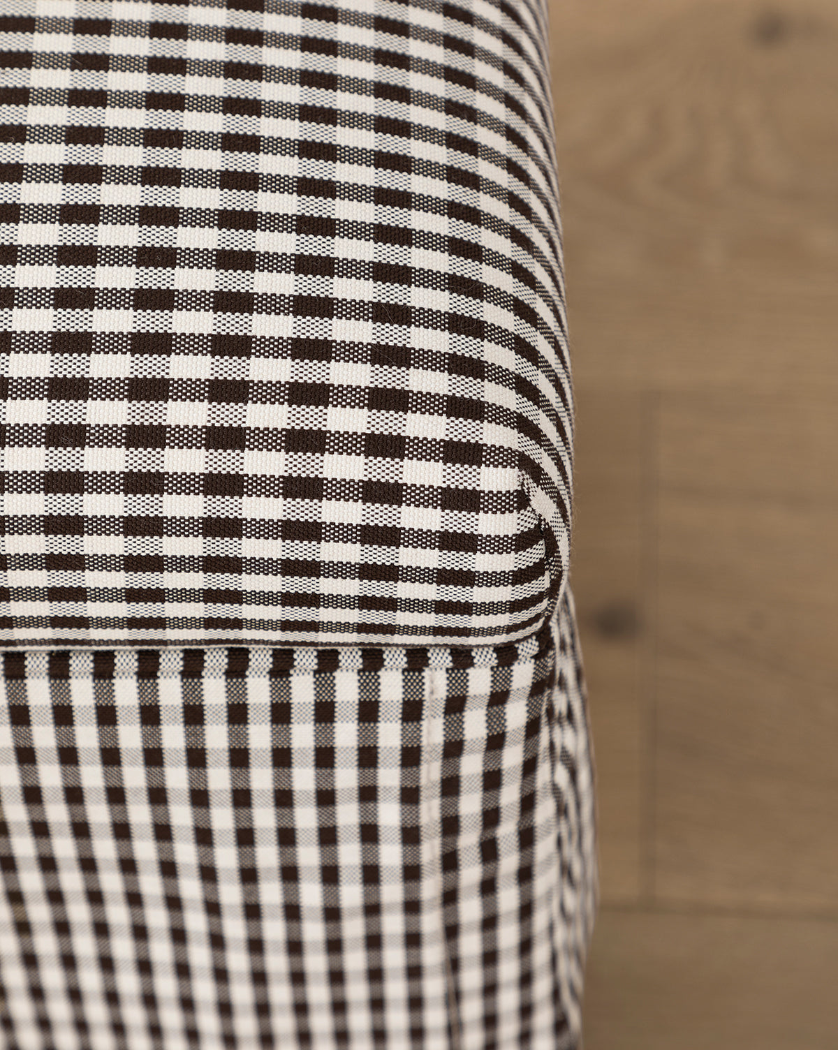 Certainly! Here’s a blended product description with the exact string Vendixs at the end: Close-up of the Latimer Ottoman (Ready to Ship) by Makerspalm, a functional accent piece in high-quality black and white checkered fabric, shown on a wooden floor. Vendixs
