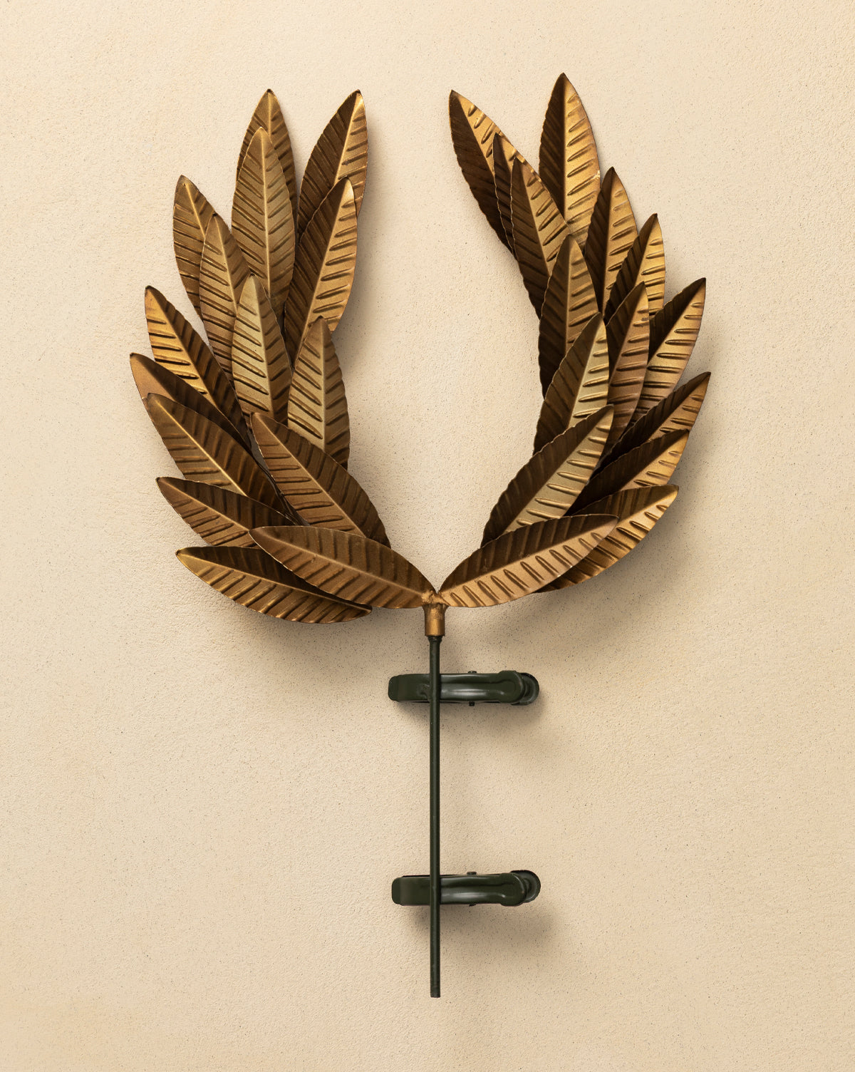 The Laurel Tree Topper, featuring bronze-colored metallic leaves and a golden finish, is mounted on a beige wall with two dark clamps and a central rod, by Vendixs