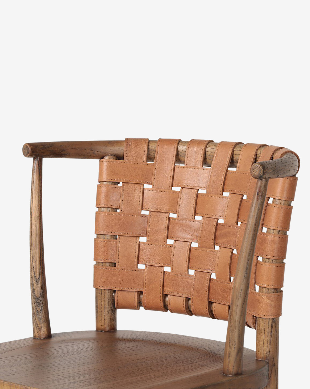 The Lennon Dining Chair features a compact wooden frame, rounded smooth arms, and a woven crisscross backrest made of tan leather straps, complemented by a sturdy wooden seat, by Vendixs