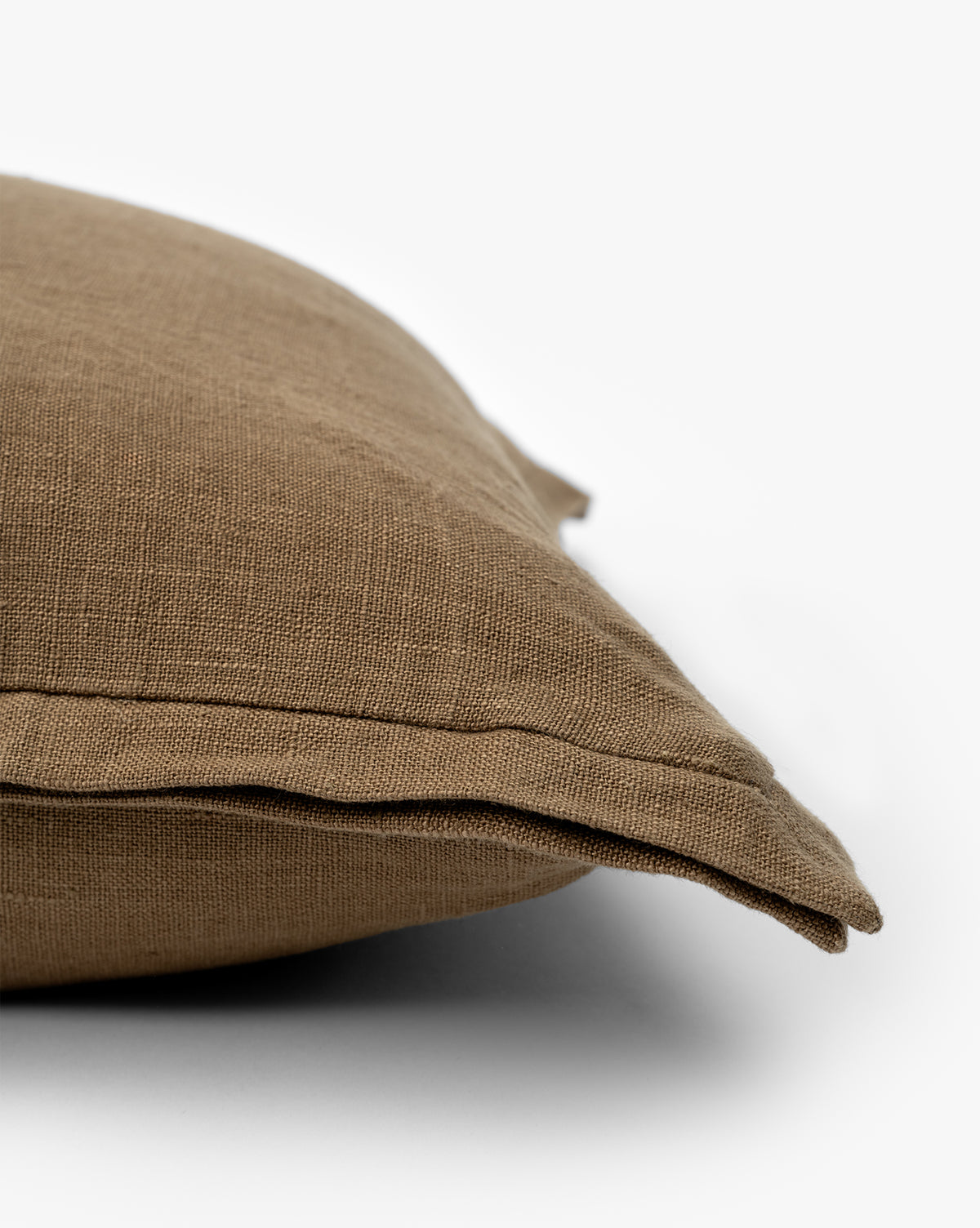 A close-up of the Liam Double Flange Pillow Cover in brown highlights its textured linen fabric, visible double flange detail, and intricate corner design against a white background, by Vendixs