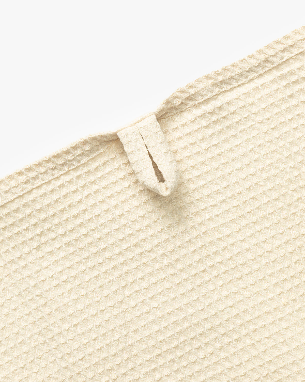 Close-up of the Linen Blend Waffle Tea Towel in beige, featuring a textured surface and a small hanging loop near the edge. This absorbent kitchen essential is shown flat on a white background, by Vendixs