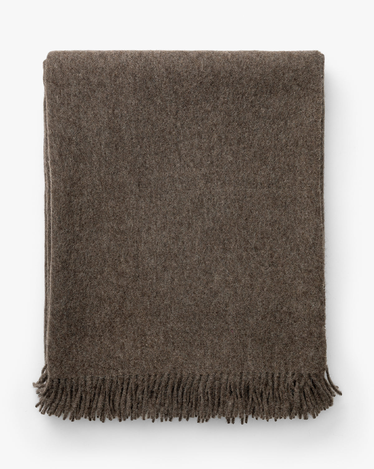 The Fibre Locester Throw is a neatly folded, brown recycled alpaca blanket with short fringe along the bottom edge, displayed on a white background. Vendixs