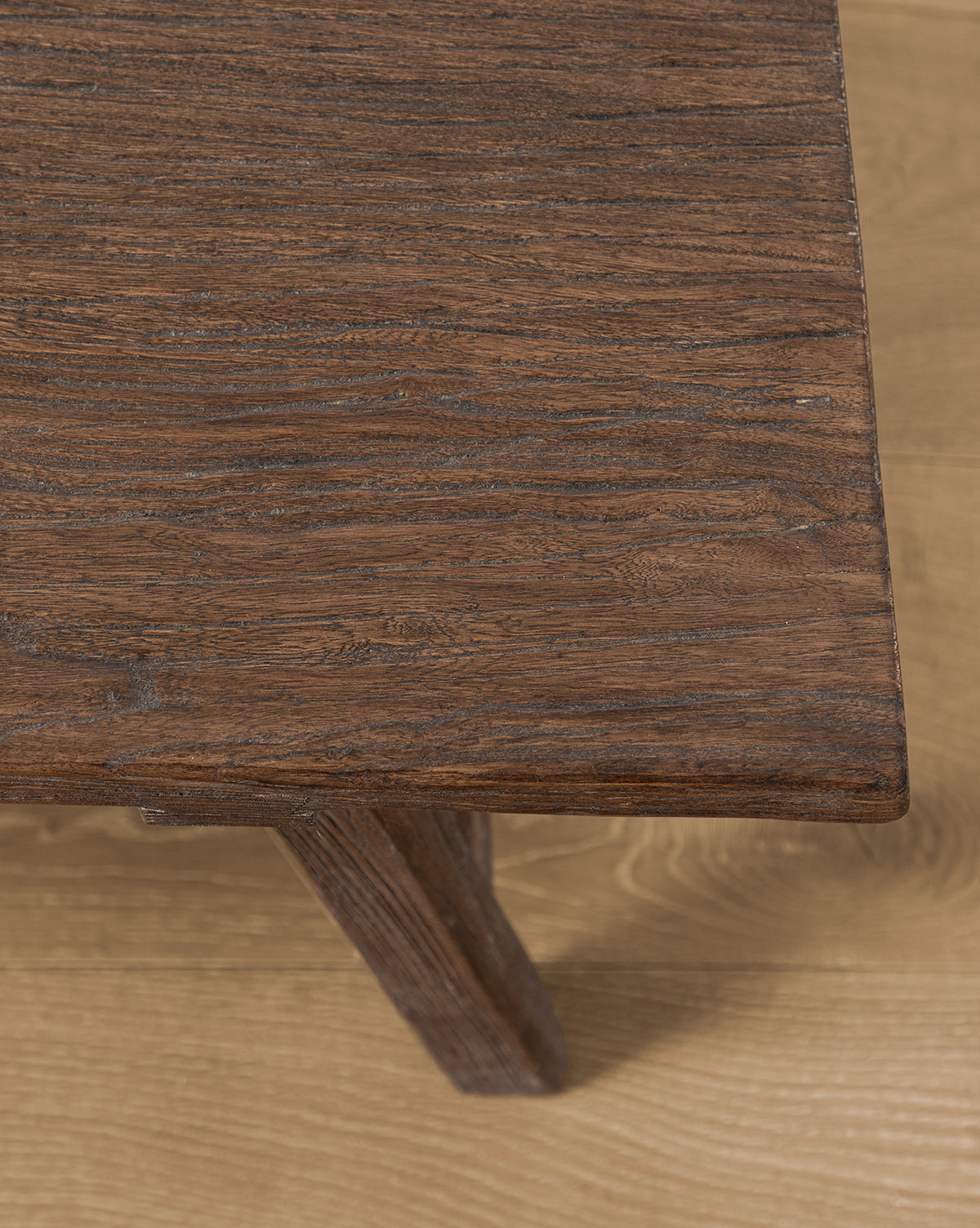 A close-up of the Lockwood Coffee Table’s corner showcases its rustic charm and rich brown finish, highlighting the wood grain detail. The table sits on a light-colored wooden floor, by Vendixs
