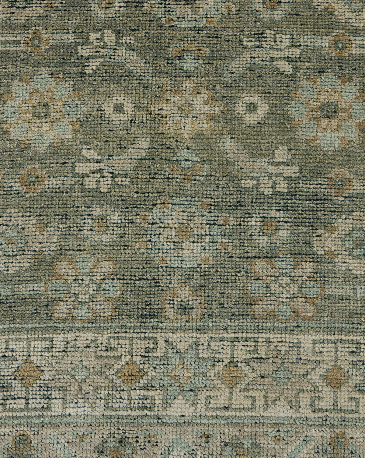A close-up of the Loreo Hand-Knotted Wool Rug highlights its intricate geometric and floral patterns in soft green, beige, and blue tones, showcasing the artisan craftsmanship and detailed woven texture, by Vendixs