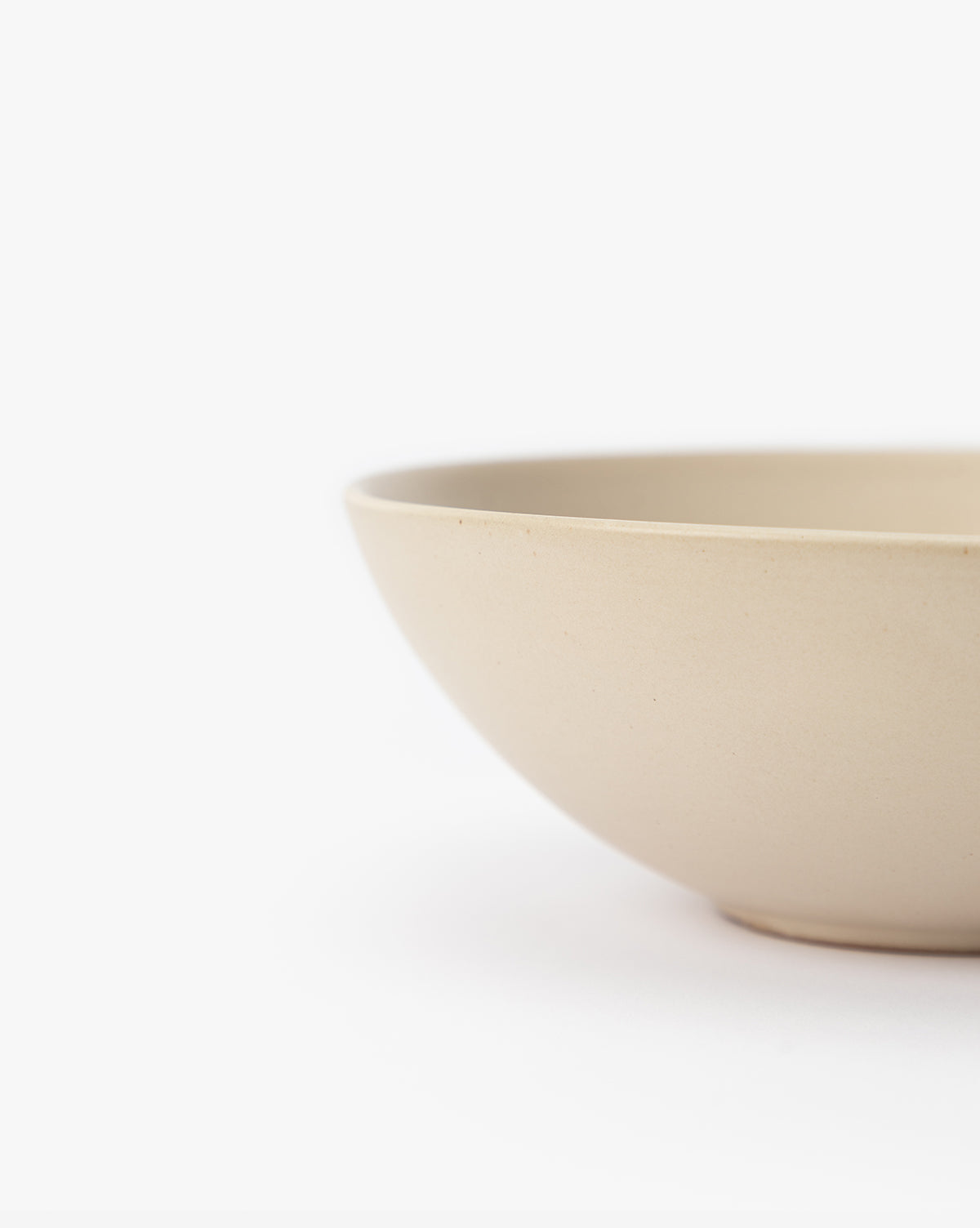 A close-up of the Luana Bowl, crafted from glazed stoneware in a modern neutral palette, showcases its smooth surface and timeless simplicity against a white background, with only part of the bowl visible on the right, by Vendixs