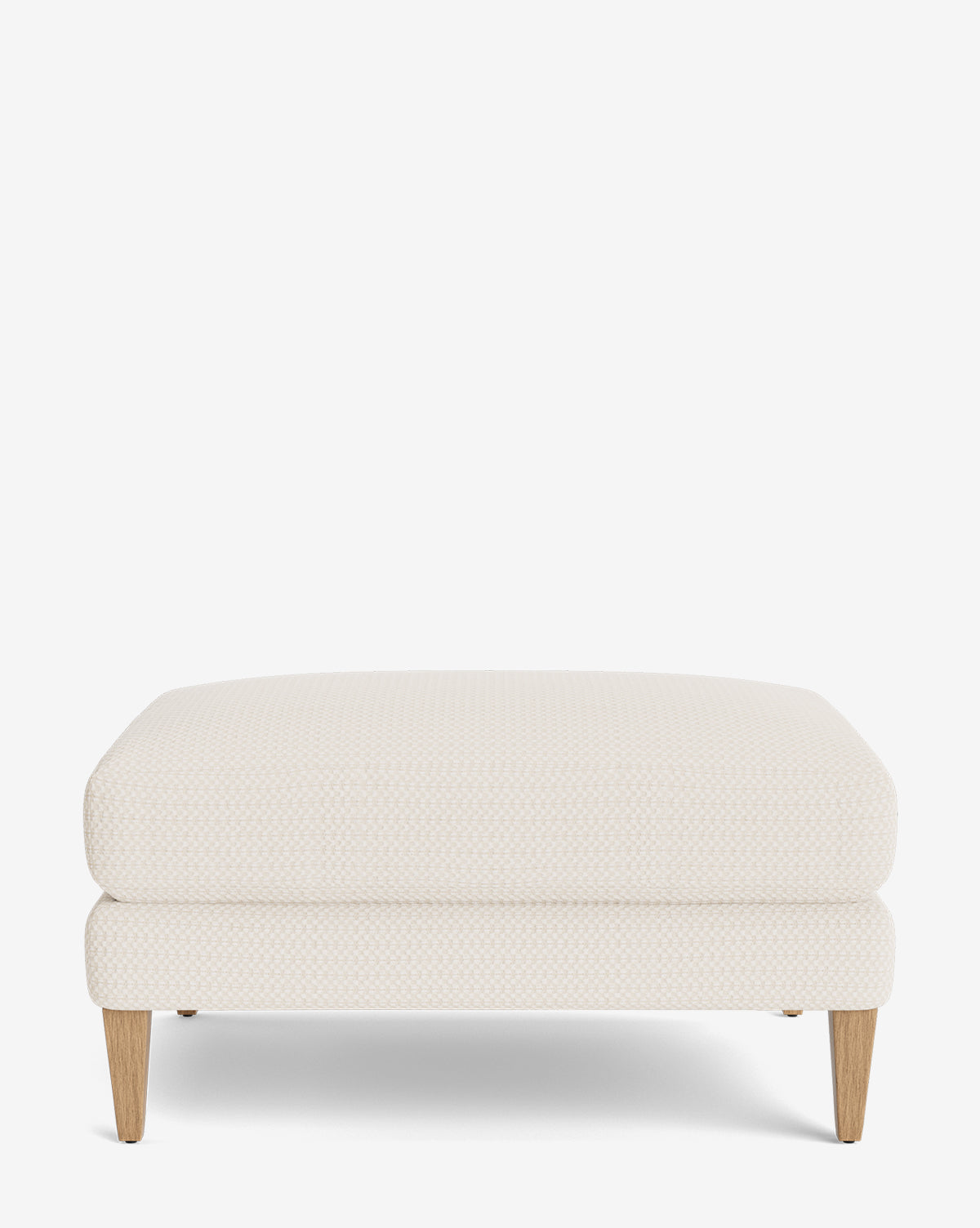 The Lucille Ottoman, with customizable light beige upholstery and four light wooden legs, adds a modern touch, by Vendixs Displayed on a plain white background.
