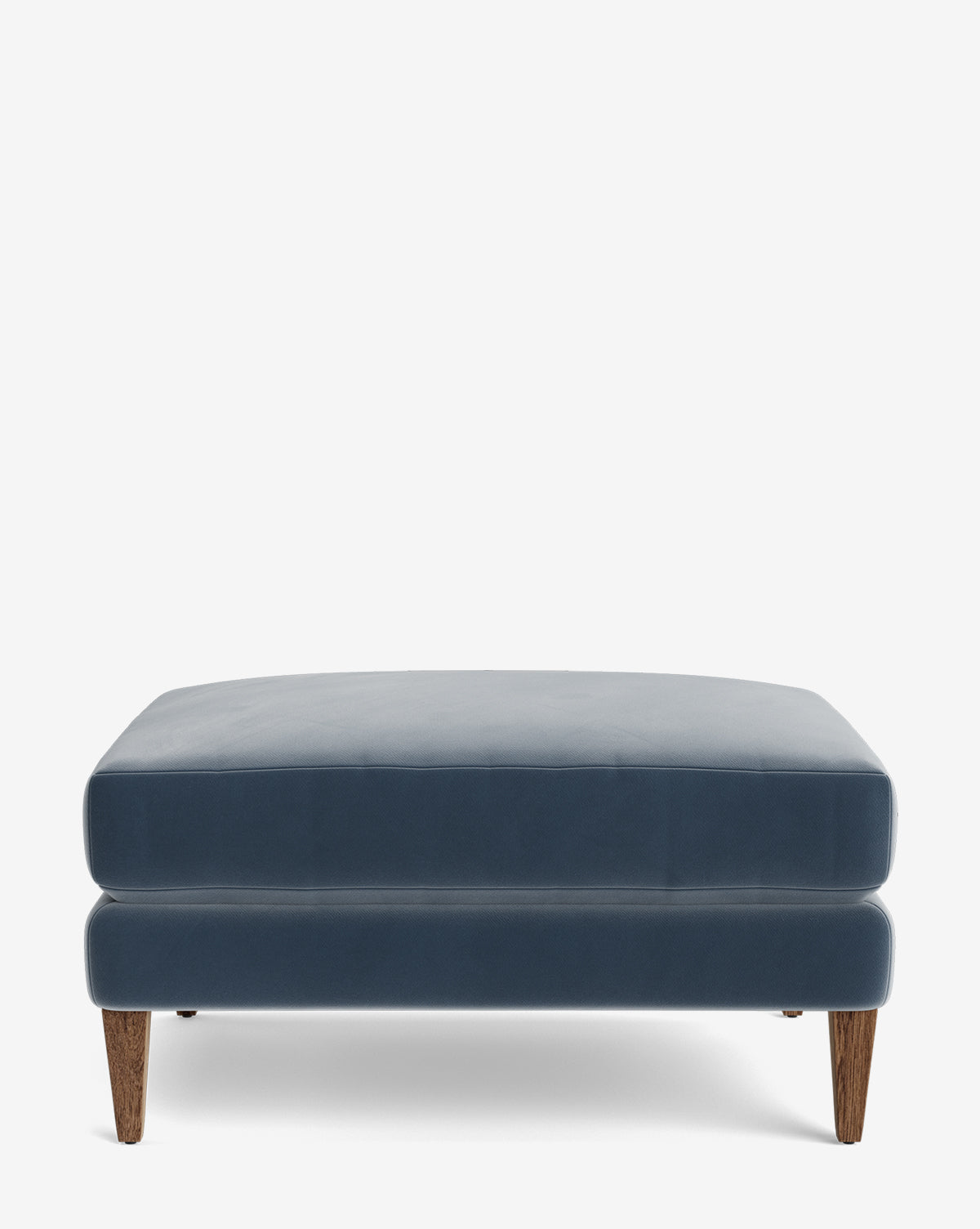 The Lucille Ottoman is a modern rectangular ottoman in blue with short wooden legs, displayed on a plain white background by McGee & Co.