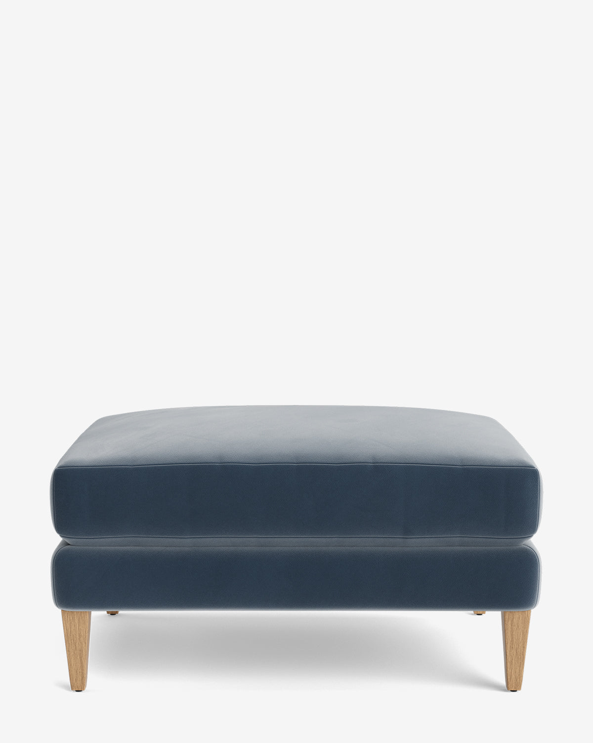 The Lucille Ottoman is a modern rectangular blue velvet piece with light wooden tapered legs, displayed on a plain white background—perfect for adding style and comfort to any space, by Vendixs