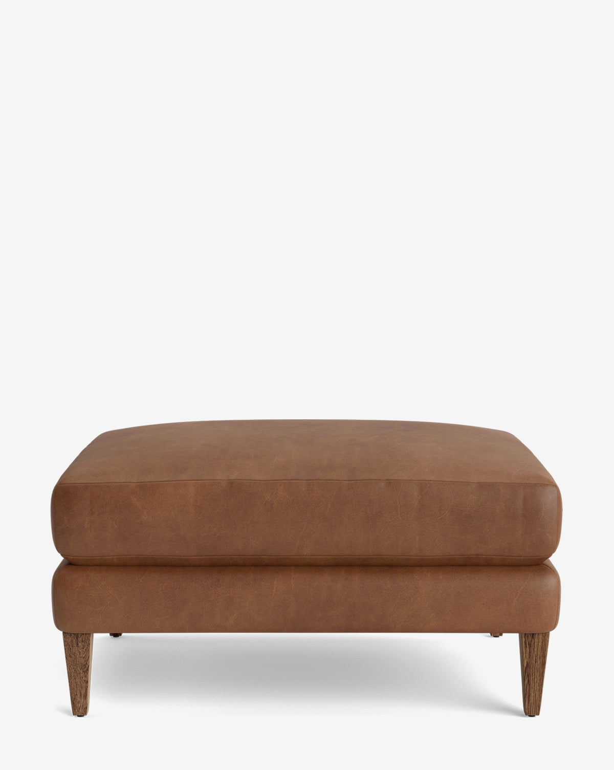 The Lucille Ottoman is a modern, rectangular ottoman with brown leather upholstery and wooden legs, featuring a minimalist design that suits any contemporary space. It is shown against a plain white background by McGee & Co.