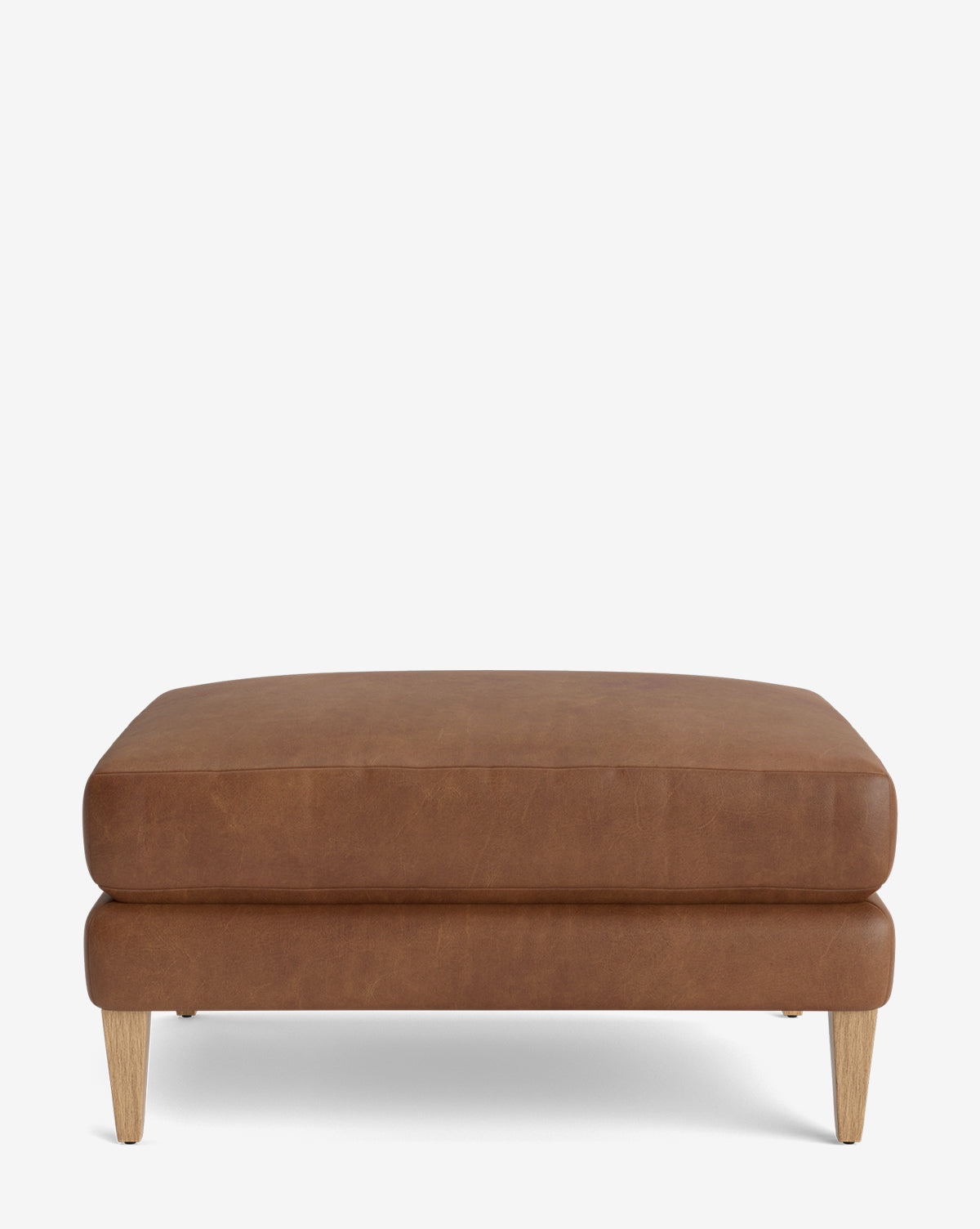 The Lucille Ottoman features a minimalist, modern design with a rectangular brown leather seat and wooden legs. It is customizable and displayed against a plain white background, by Vendixs