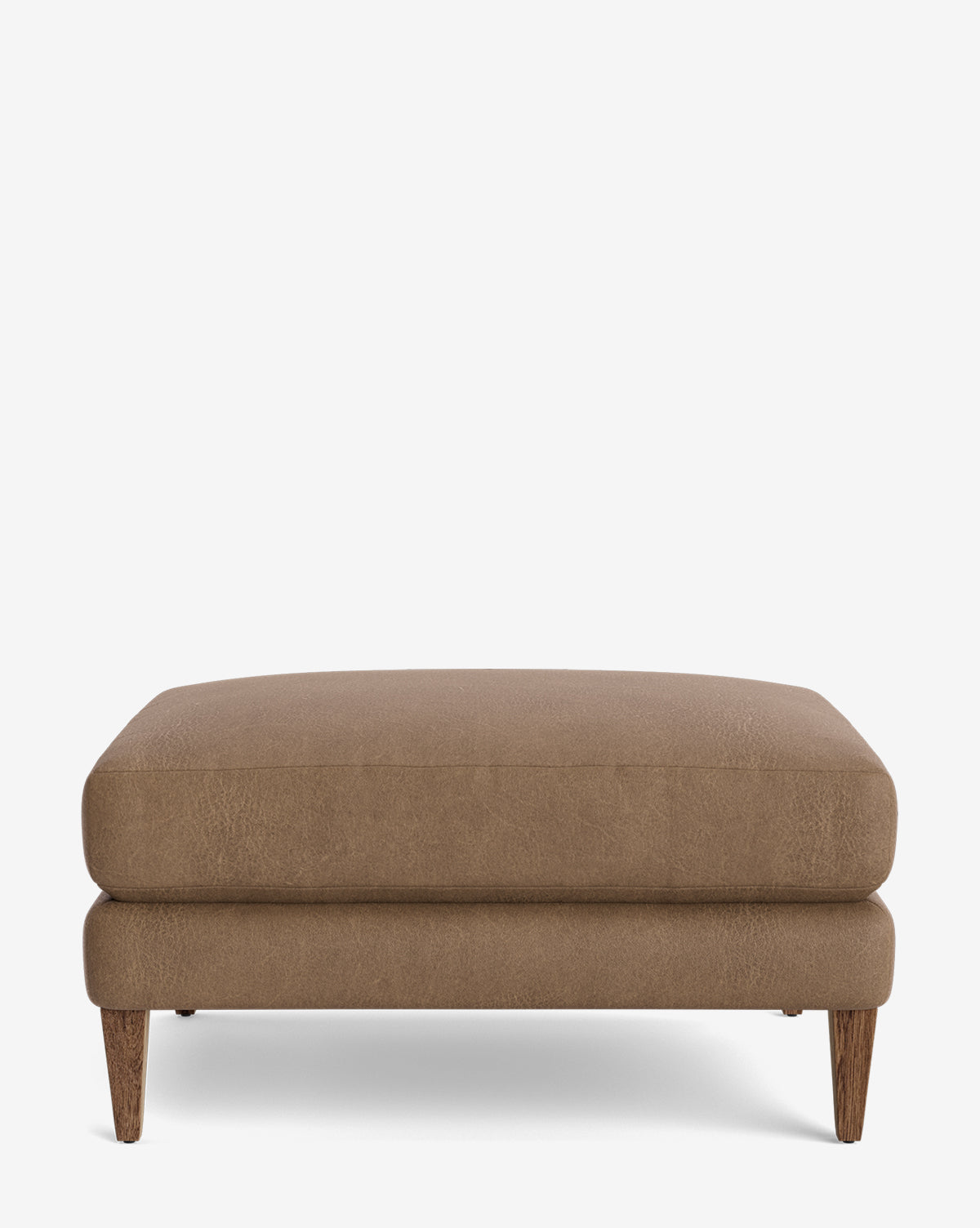The Lucille Ottoman is a modern, rectangular ottoman with a cushioned top and four tapered wooden legs, displayed on a plain white background by McGee & Co.