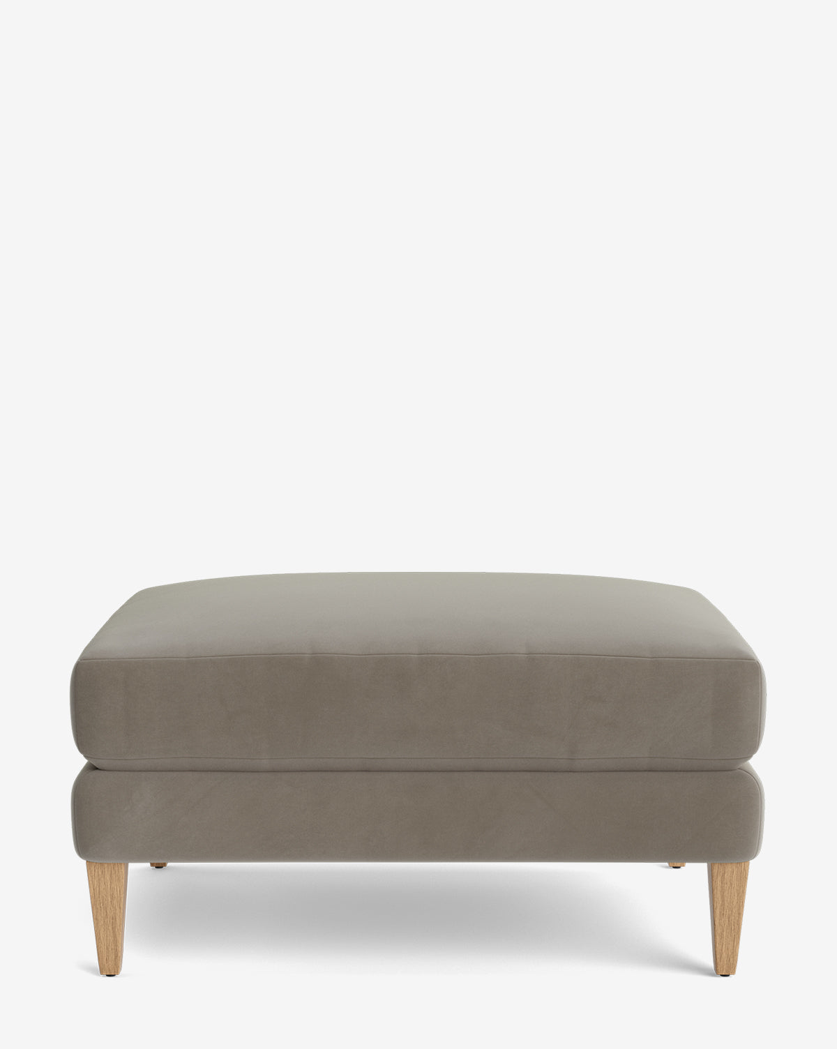 The Lucille Ottoman features modern light brown upholstery and four angled wooden legs, displayed on a plain white background, by Vendixs