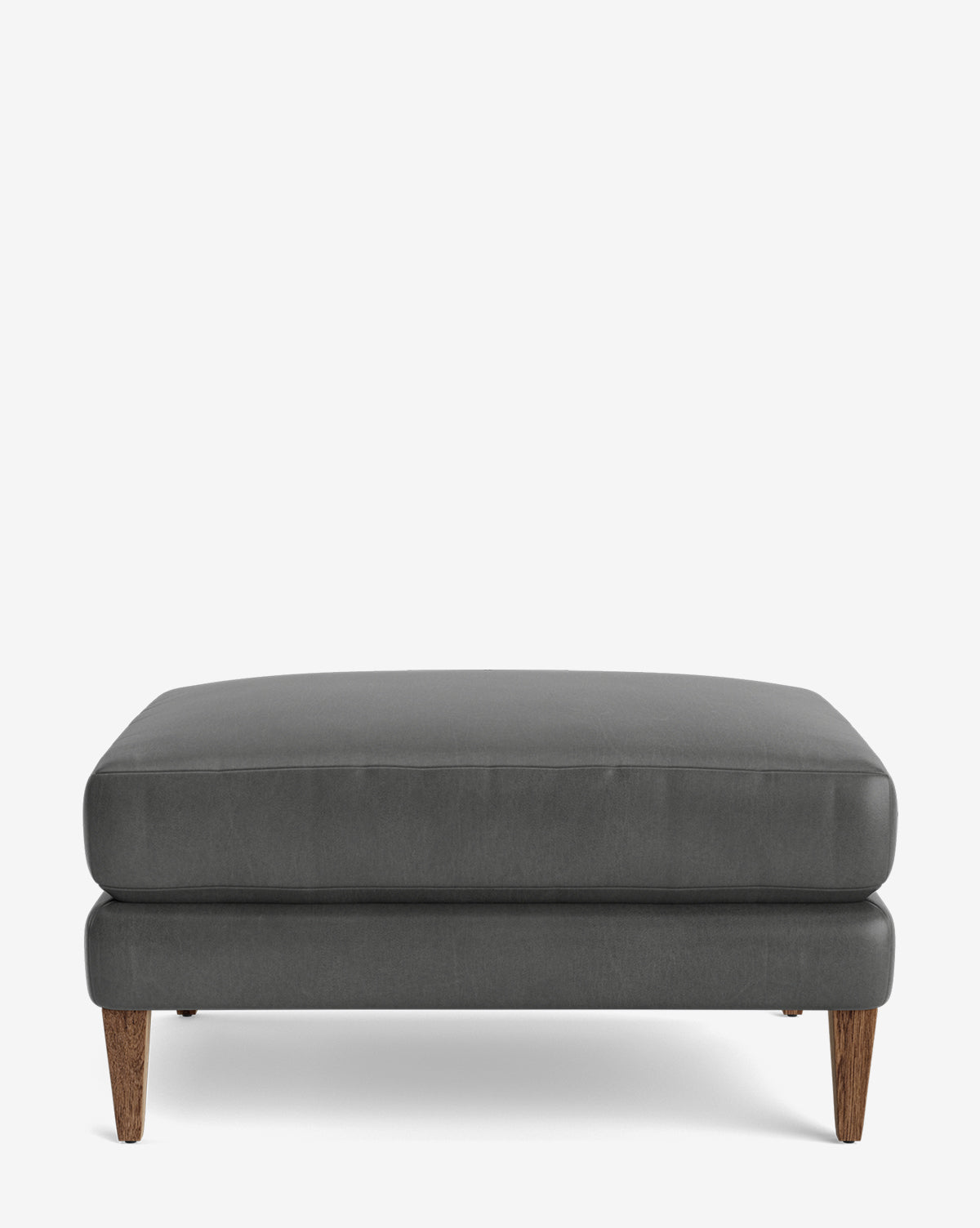 The Lucille Ottoman is a modern rectangular ottoman with dark gray upholstery, wooden legs, and customizable options, shown against a plain white background, by Vendixs