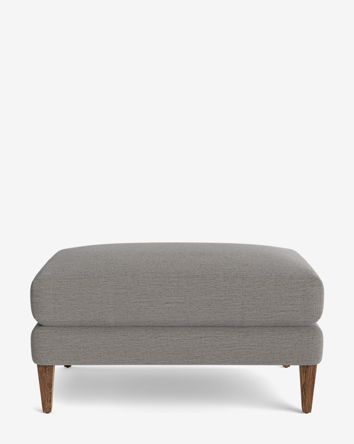 The Lucille Ottoman features a modern rectangular design with light gray upholstery and four tapered wooden legs. Customizable and stylish, it adds versatile charm to any contemporary space, by McGee & Co.