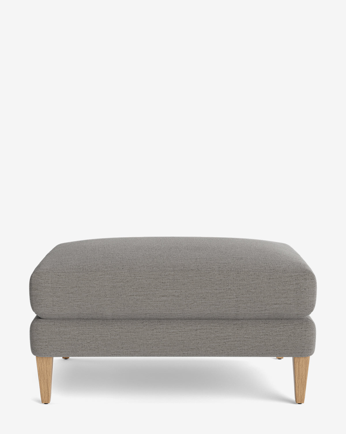 The Lucille Ottoman is a customizable rectangular grey upholstered ottoman with light wooden tapered legs, shown against a plain white background—a modern, versatile piece for any room, by Vendixs