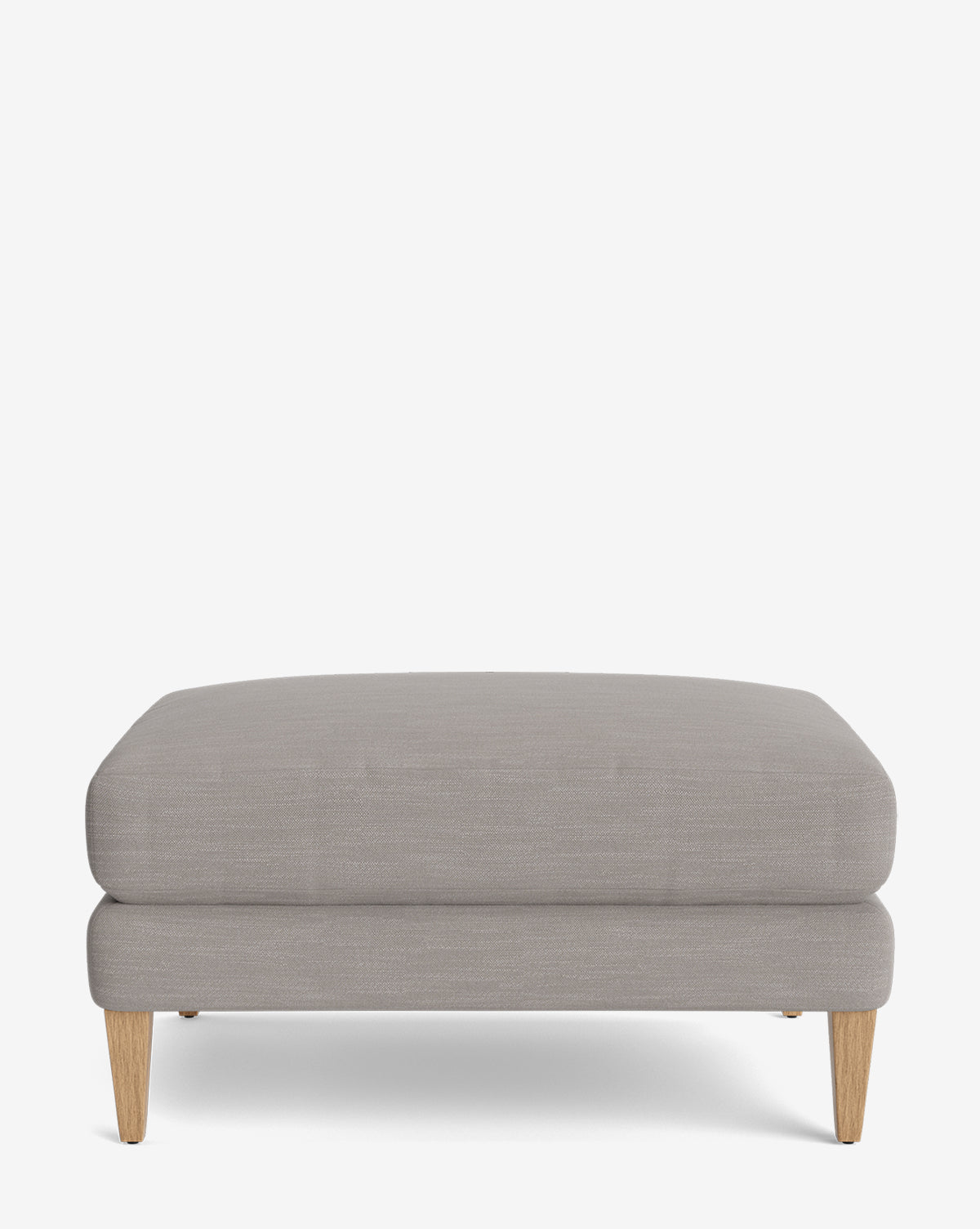 The Lucille Ottoman features light gray upholstery and four short, angled wooden legs, shown against a plain white background—a stylish and customizable choice for modern spaces, by Vendixs