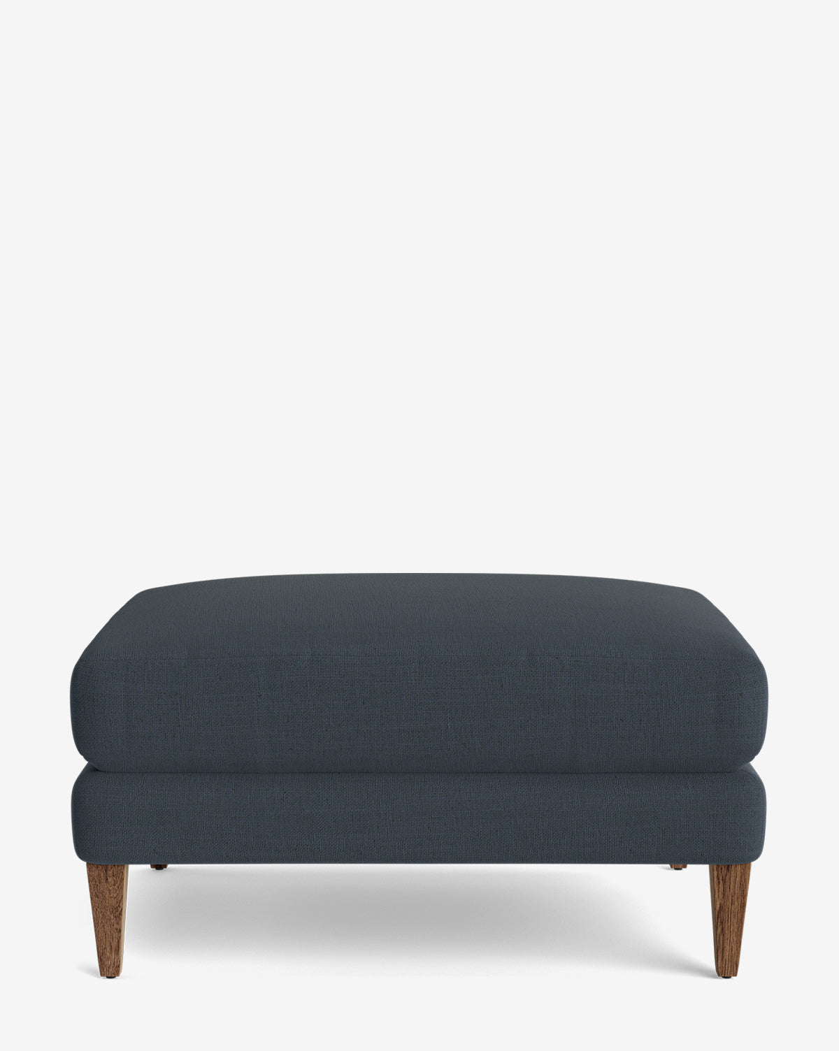 The Lucille Ottoman is a modern, dark blue rectangular ottoman featuring a cushioned top and wooden tapered legs, displayed on a plain white background, by Vendixs