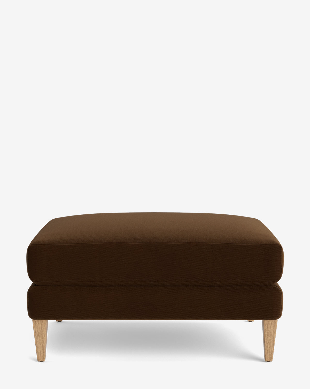 The Lucille Ottoman is a modern rectangular ottoman with a cushioned top, dark brown upholstery, and four light wood legs, shown on a plain white background by Vendixs