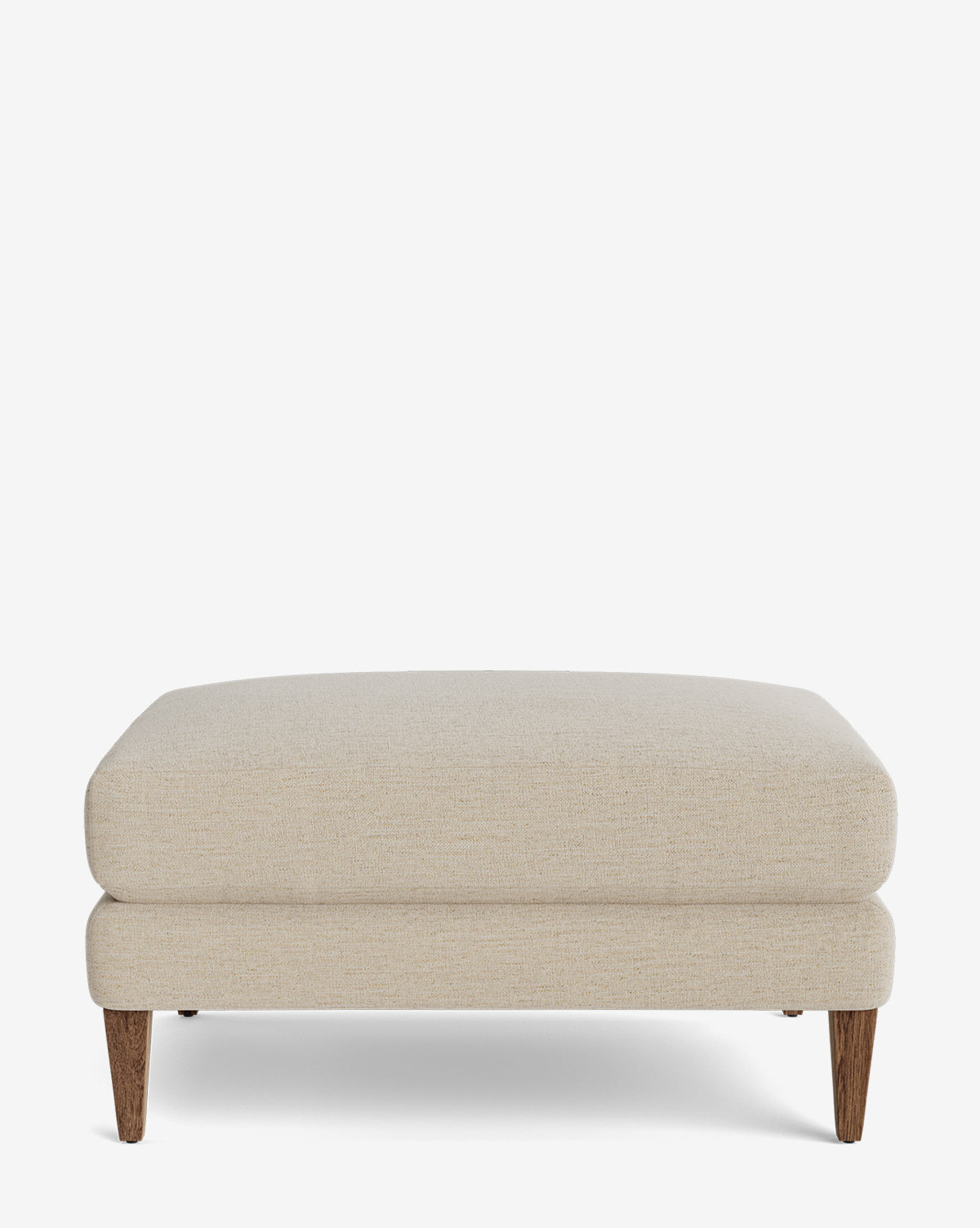 The Lucille Ottoman is a modern rectangular beige ottoman, featuring two stacked cushion layers and four tapered wooden legs, shown against a plain white background by Vendixs