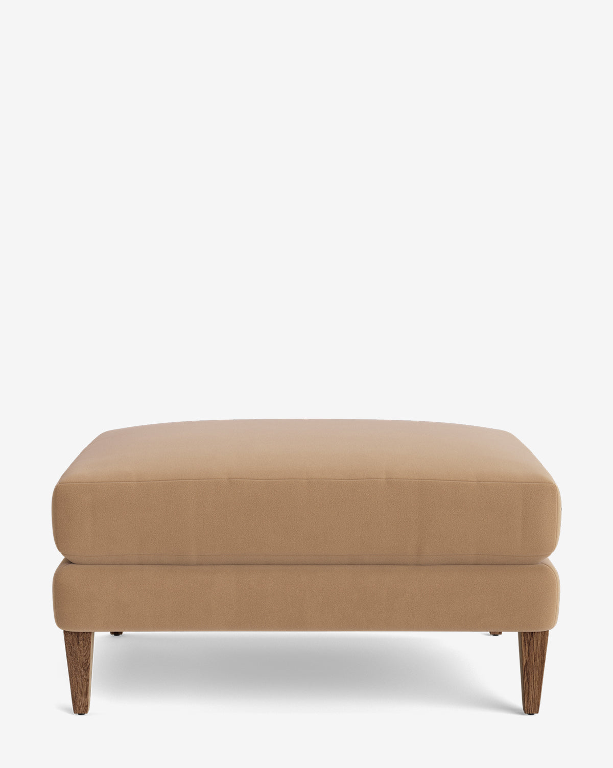 The Lucille Ottoman is a modern, rectangular ottoman in light brown with a plush cushion and short, angled wooden legs, displayed on a plain white background by McGee & Co.