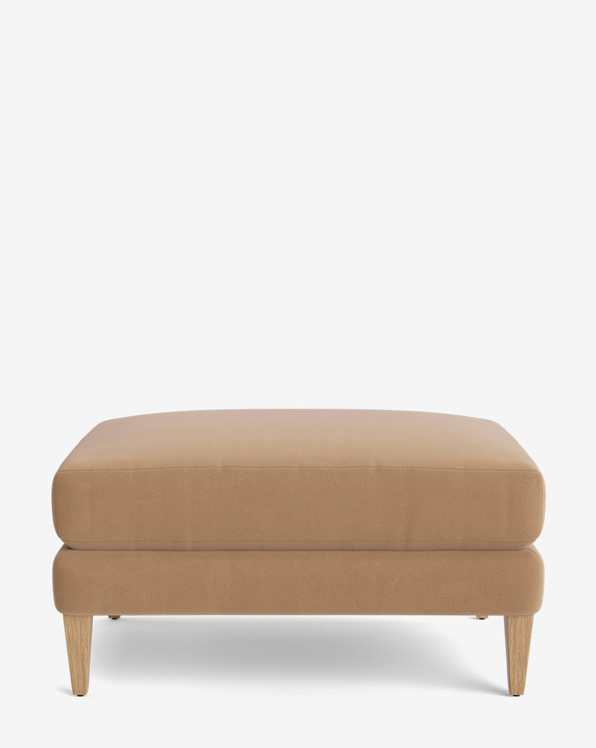 The Lucille Ottoman is a modern, rectangular tan piece with four light wooden legs. Customizable to fit your style, it offers versatility and elegance for any living space. Shown against a plain white background by McGee & Co.