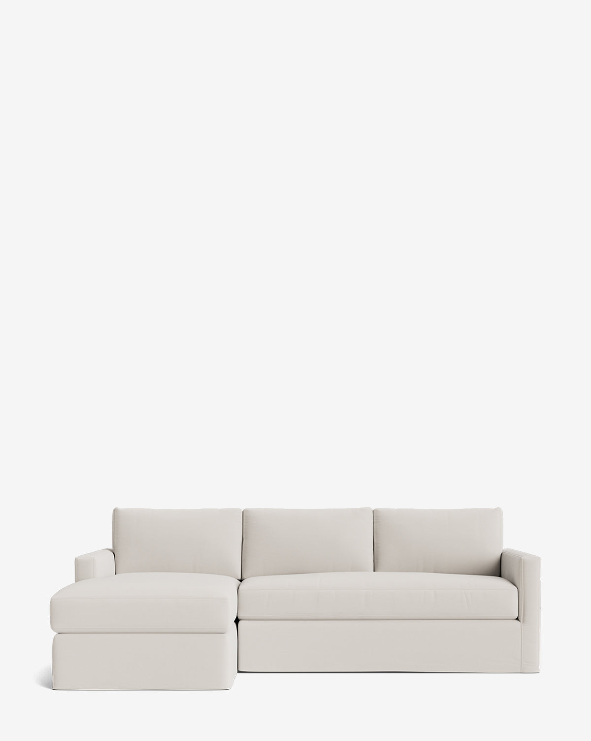 The Community Macy Slipcover Chaise Sectional 101 features a modern, light beige design with three back cushions and a left-facing chaise—customizable for versatile comfort, shown against a plain white background. Vendixs