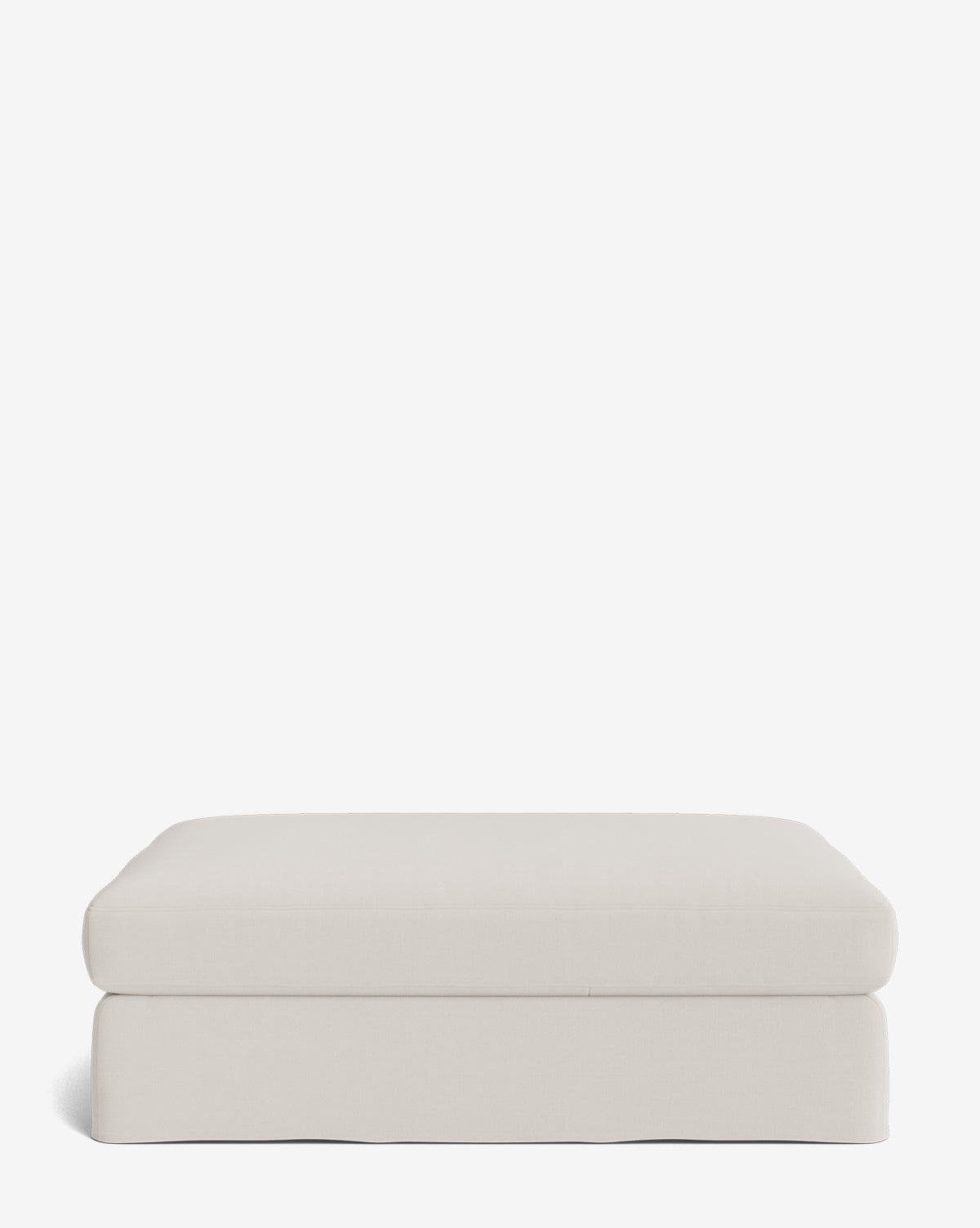 The Macy Slipcover Ottoman, in light beige fabric, features a smooth, simple rectangular design with a slightly rounded top and tailored base—an elegant addition to any living room, by Vendixs Shown against a plain white background.