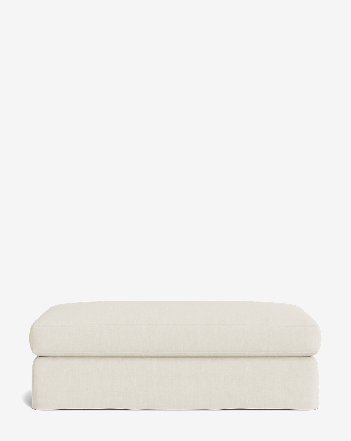 The Macy Slipcover Ottoman is a rectangular, cream-colored upholstered piece with a minimalist design—ideal for customizable living room decor—shown against a plain white background, by Vendixs