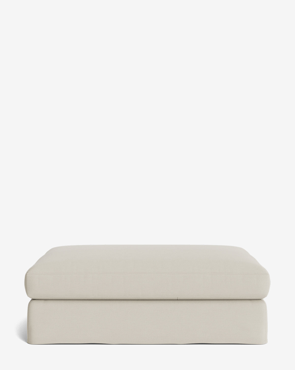 The Macy Slipcover Ottoman is a rectangular, light beige ottoman with a smooth upholstered surface, soft rounded edges, and a simple modern design. Shown against a plain white background, its perfect for any living room by McGee & Co.
