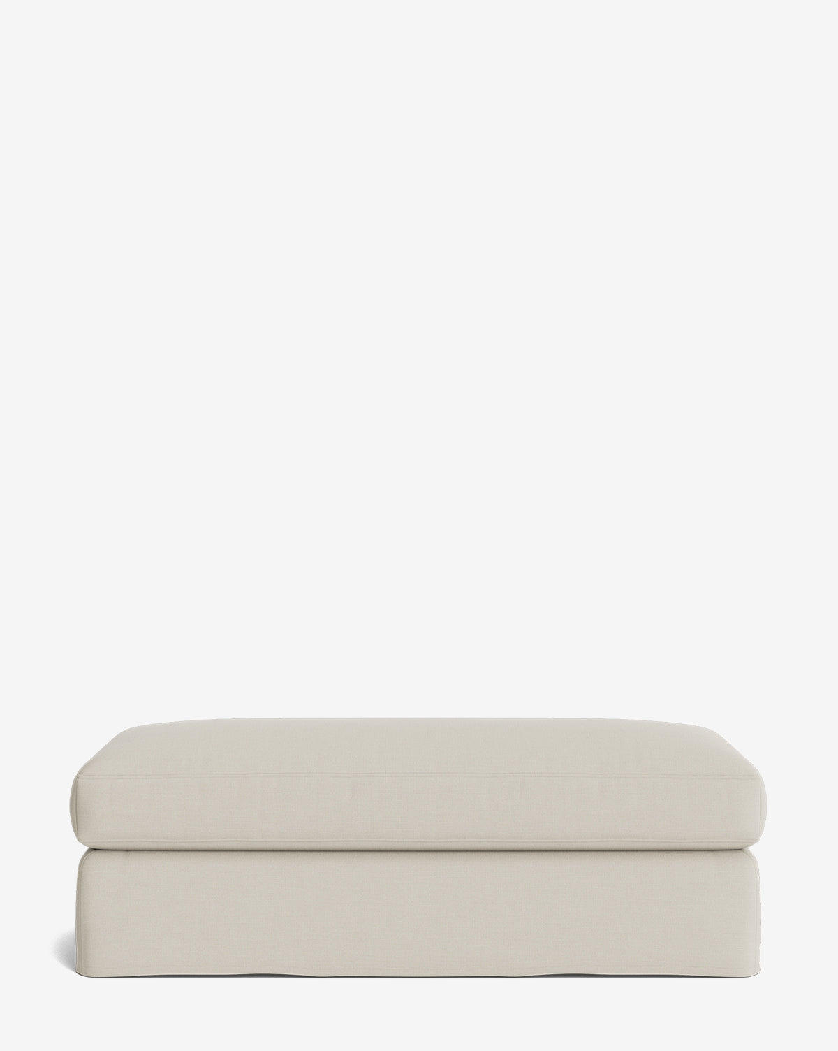 The Macy Slipcover Ottoman is a rectangular, light beige ottoman with soft, rounded edges and a smooth fabric surface—an elegant addition to any living room, shown here against a plain white background by Vendixs